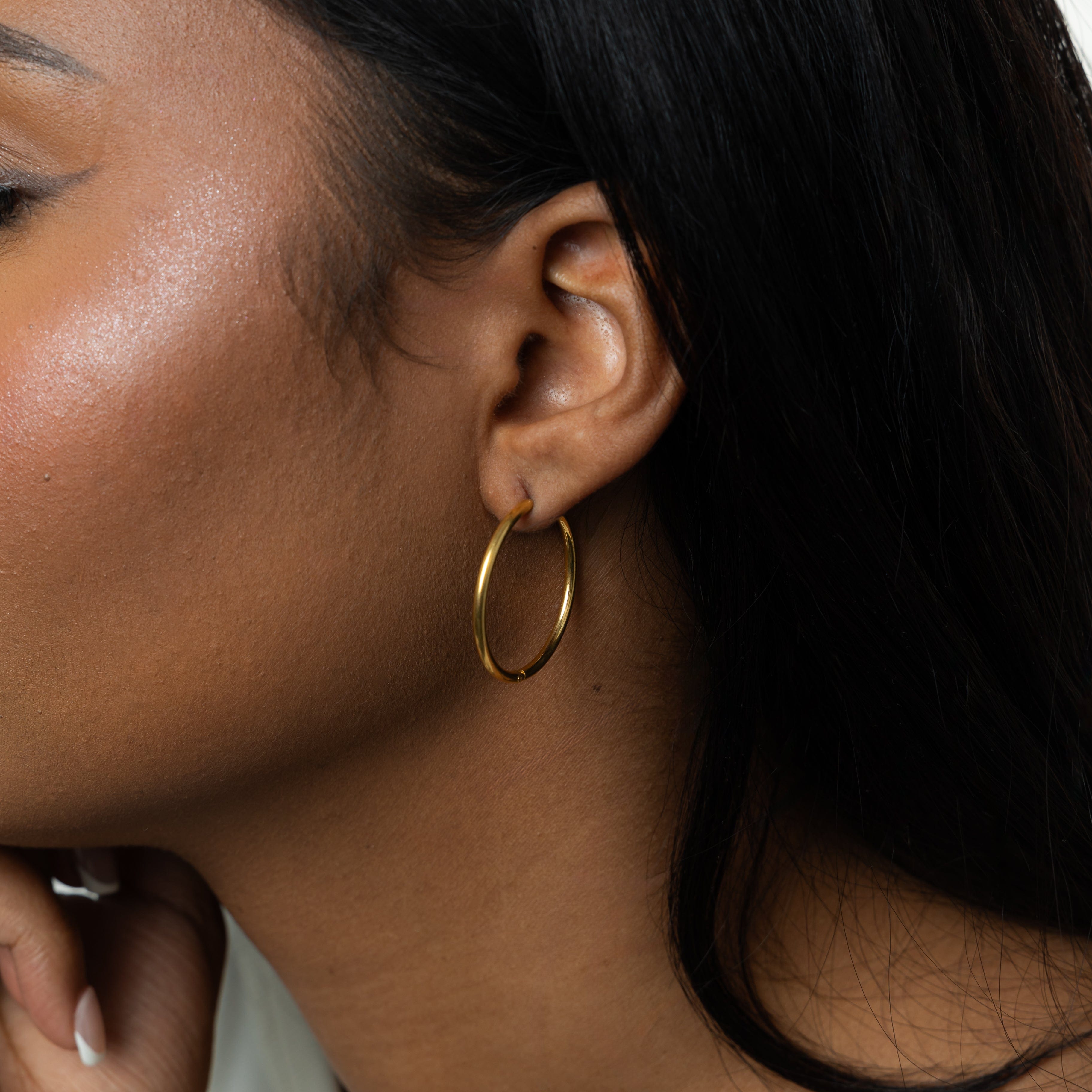 Model wearing 25mm gold hoop earrings in a casual setting, showcasing their versatility.