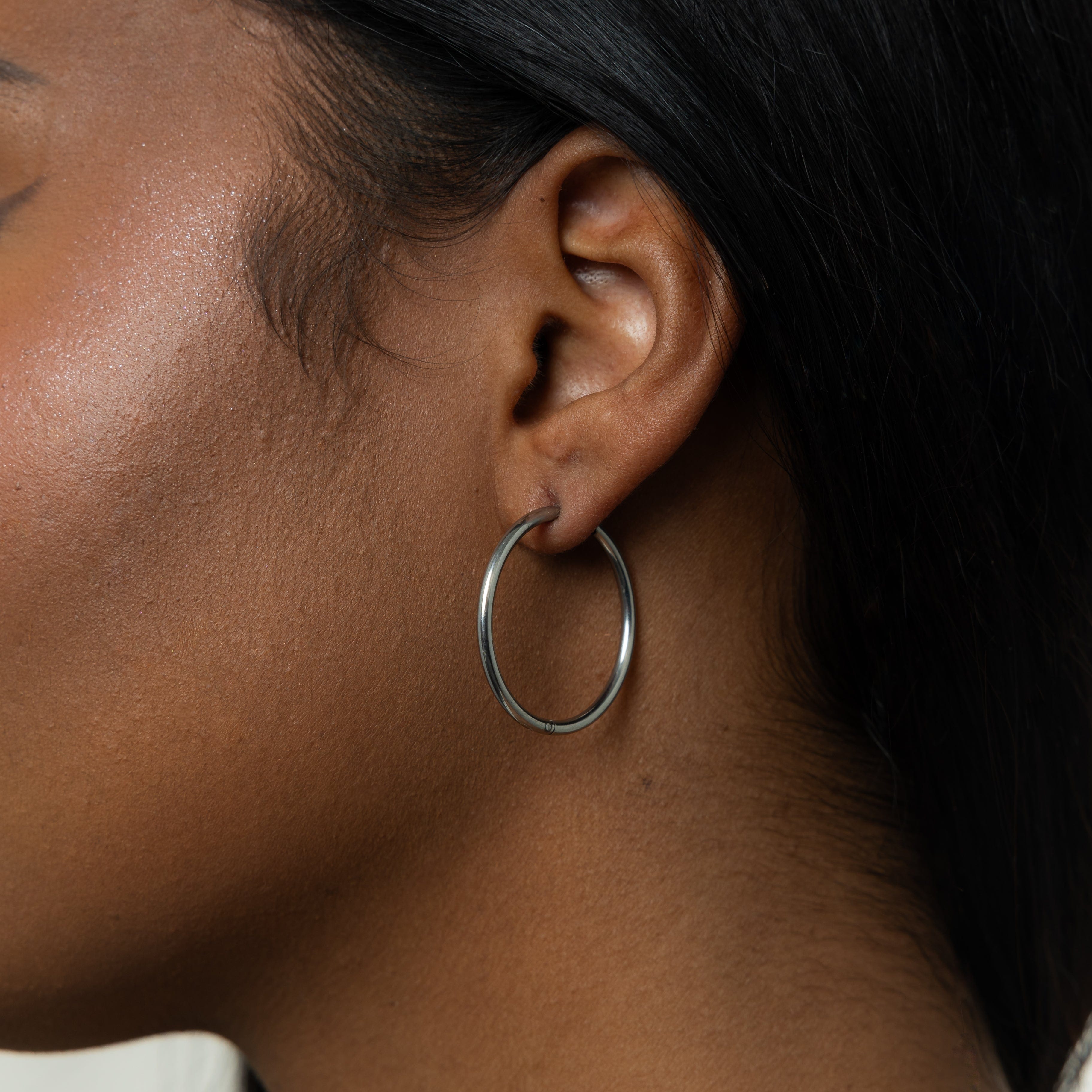 Model wearing 25mm gold hoop earrings in a casual setting, showcasing their versatility.