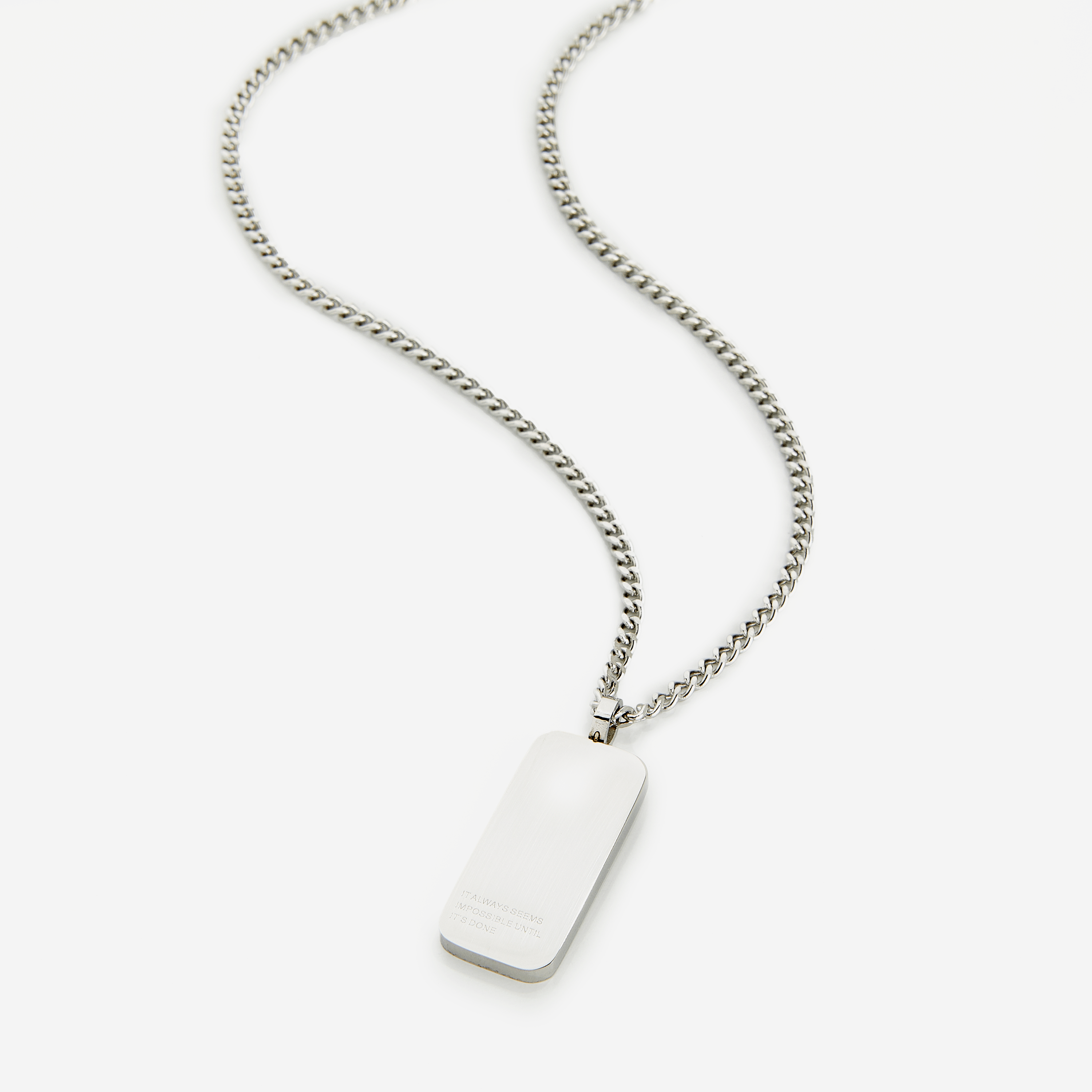 Close-up of stainless steel tag necklace resting on black velvet pouch