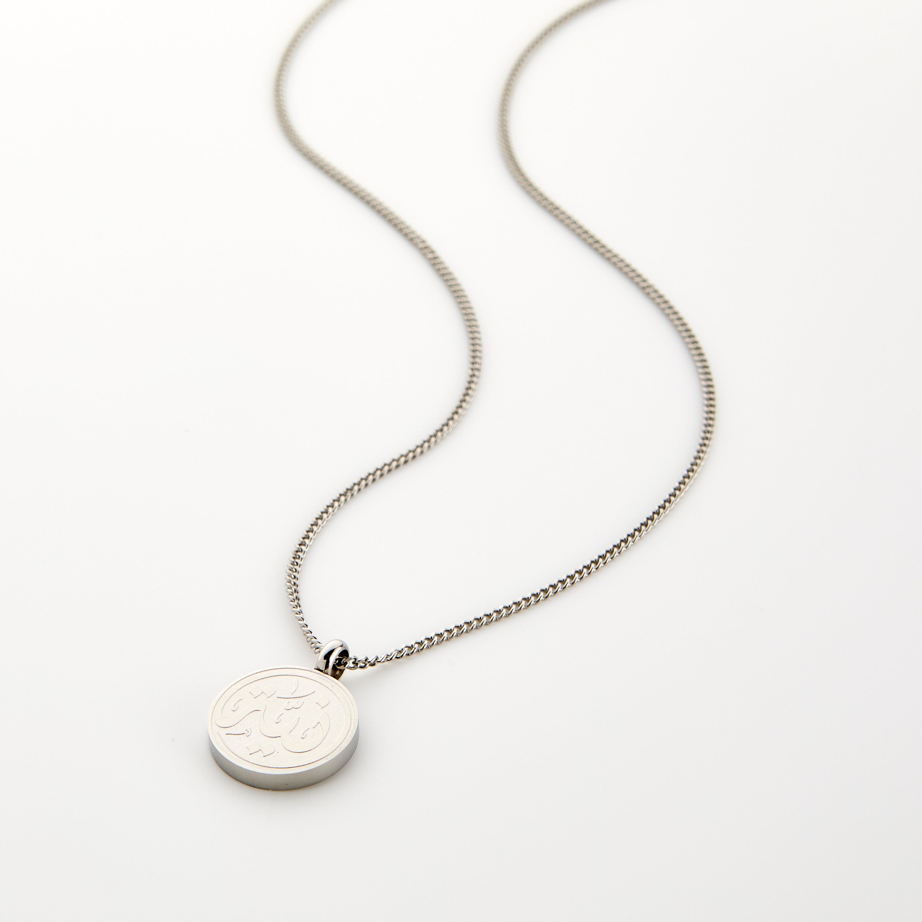Close-up of mens necklace with Arabic Niyyah calligraphy pendant on velvet pouch
