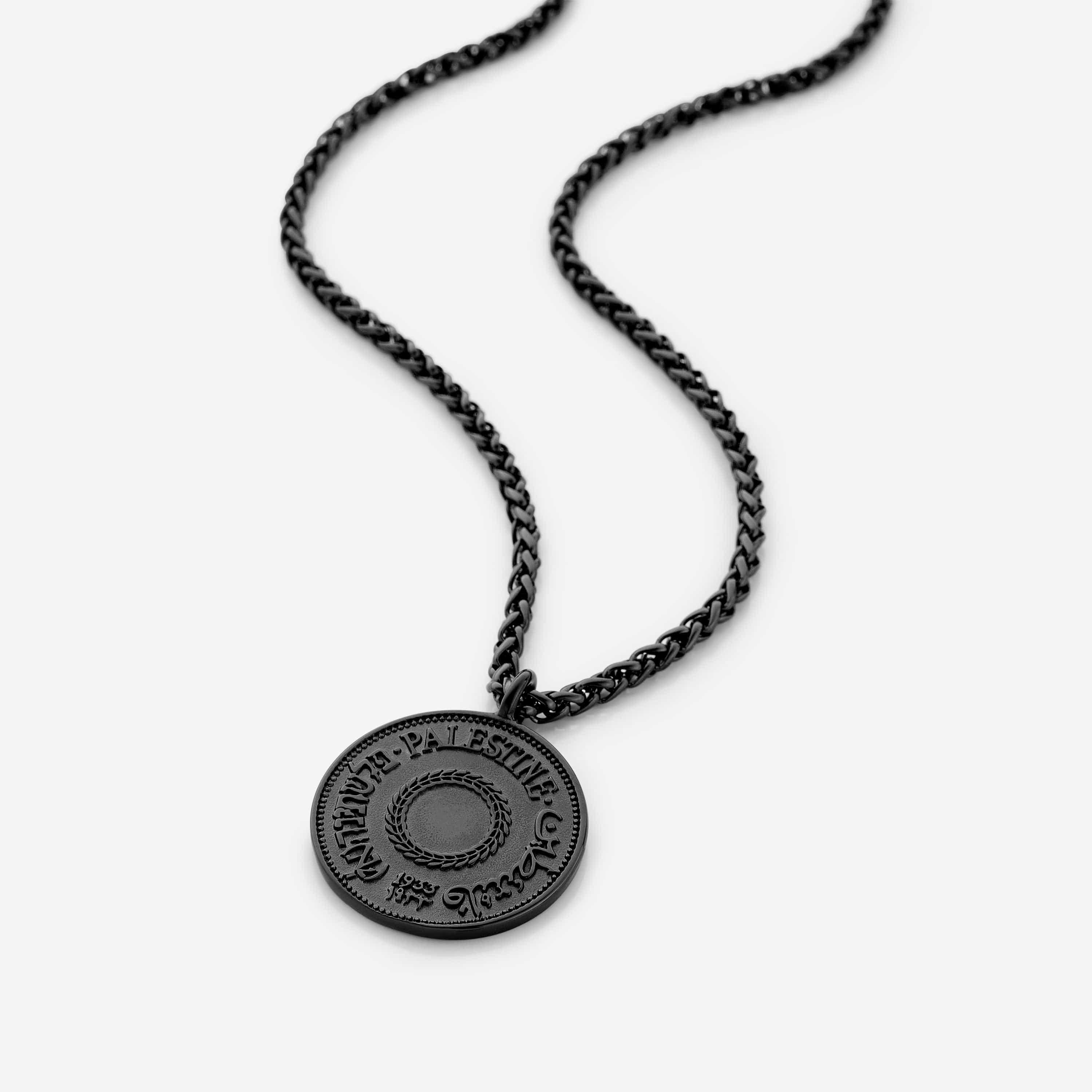 Close-up of the pendant on the mens necklace, showcasing the intricate country design against a soft surface.