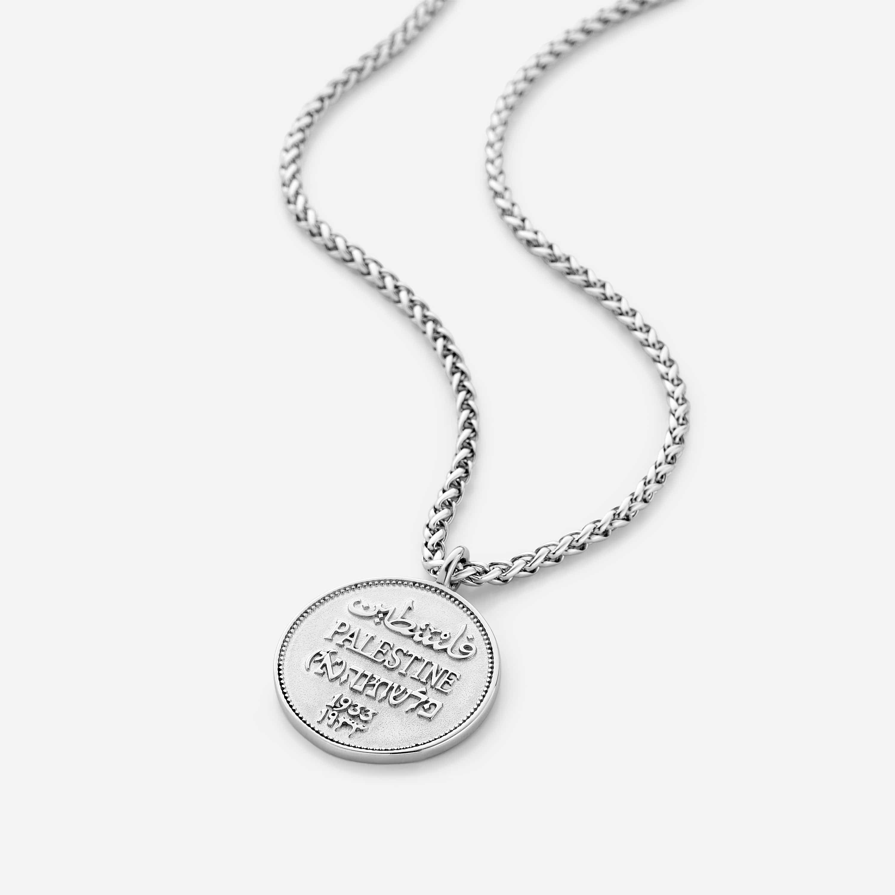 Front view of the authentic country coin necklace on a dark background, highlighting its wheat chain and pendant.