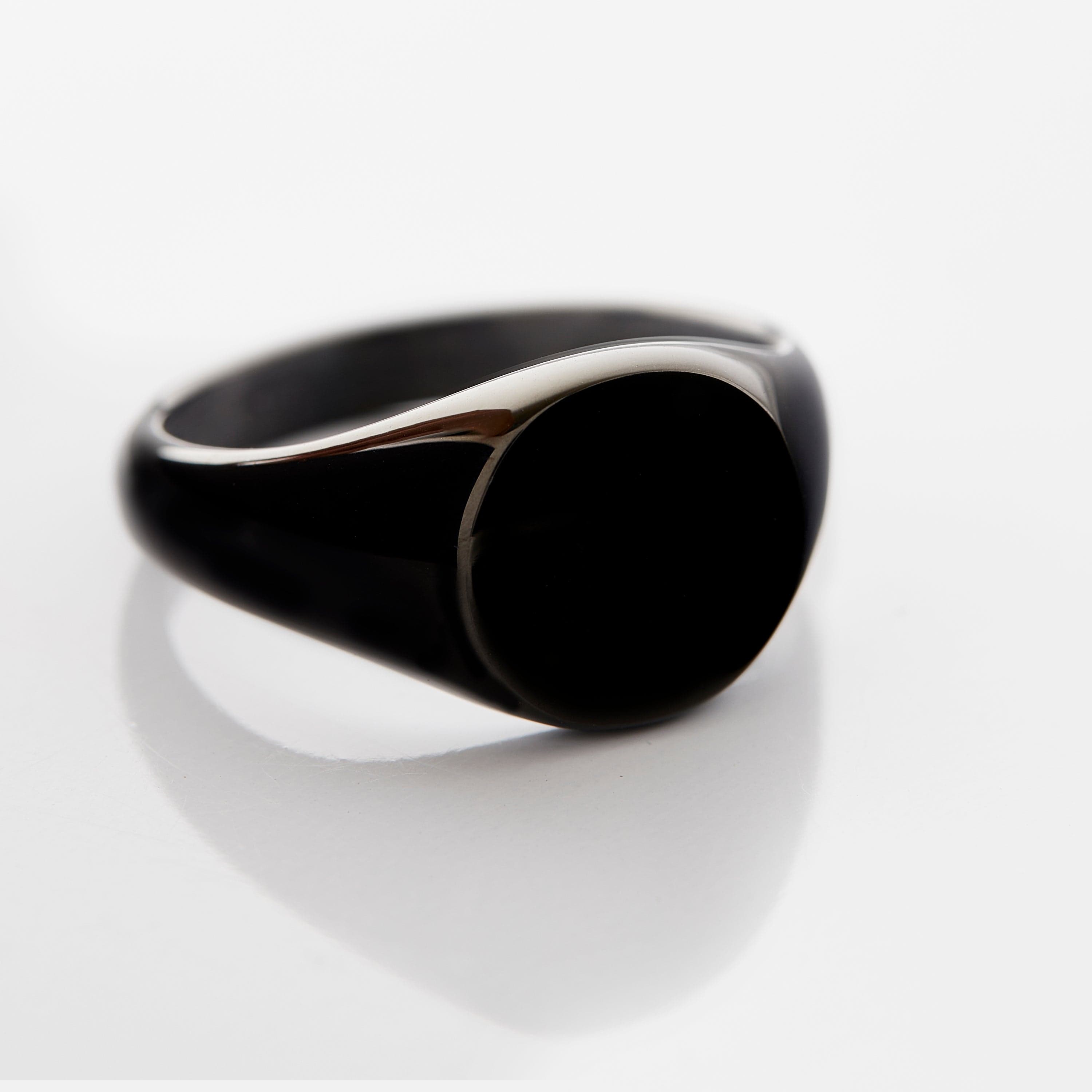 Classic round signet ring in stainless steel, displayed on a rustic wooden surface.