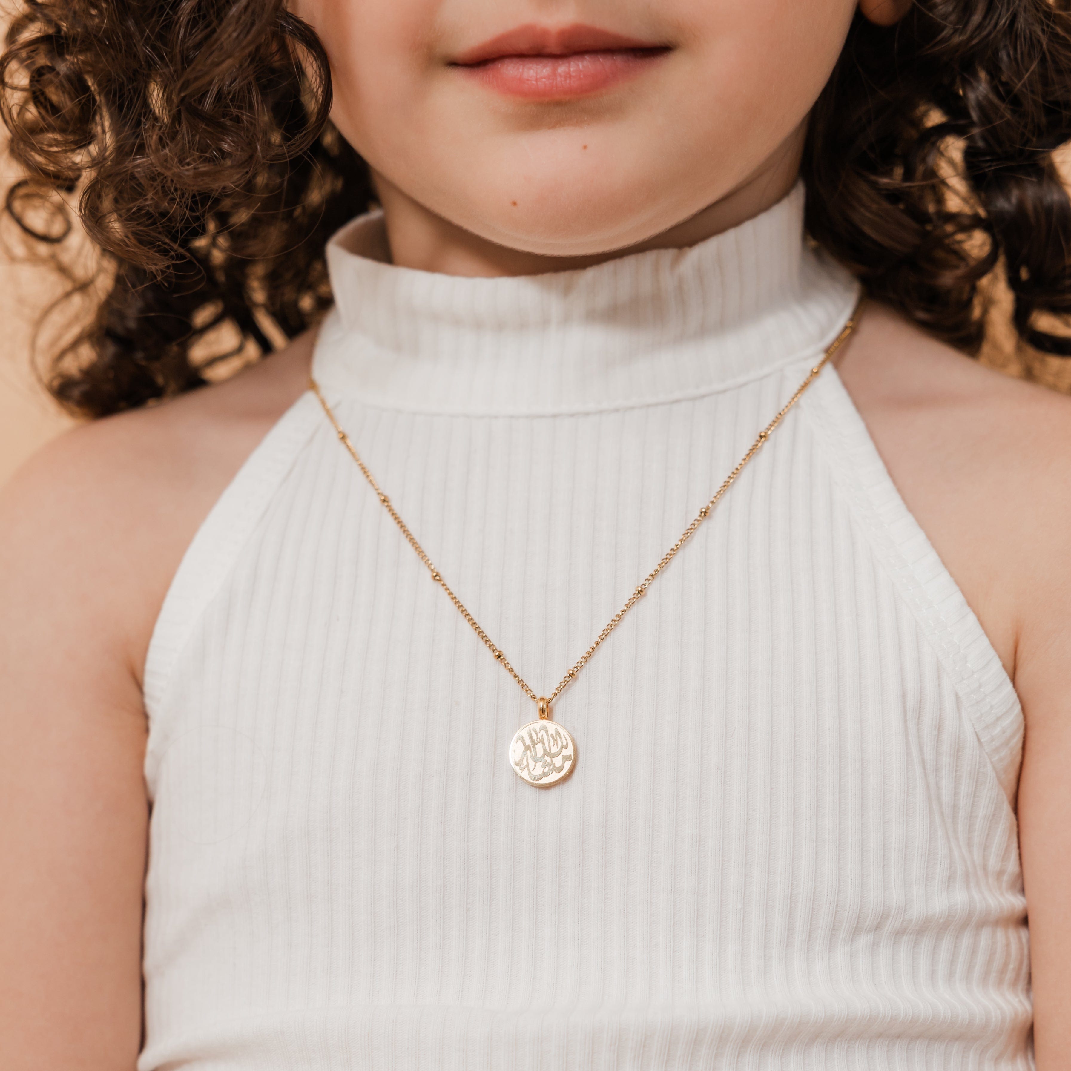 MashaAllah token necklace displayed in a velvet drawstring pouch, highlighting its gift-ready packaging.