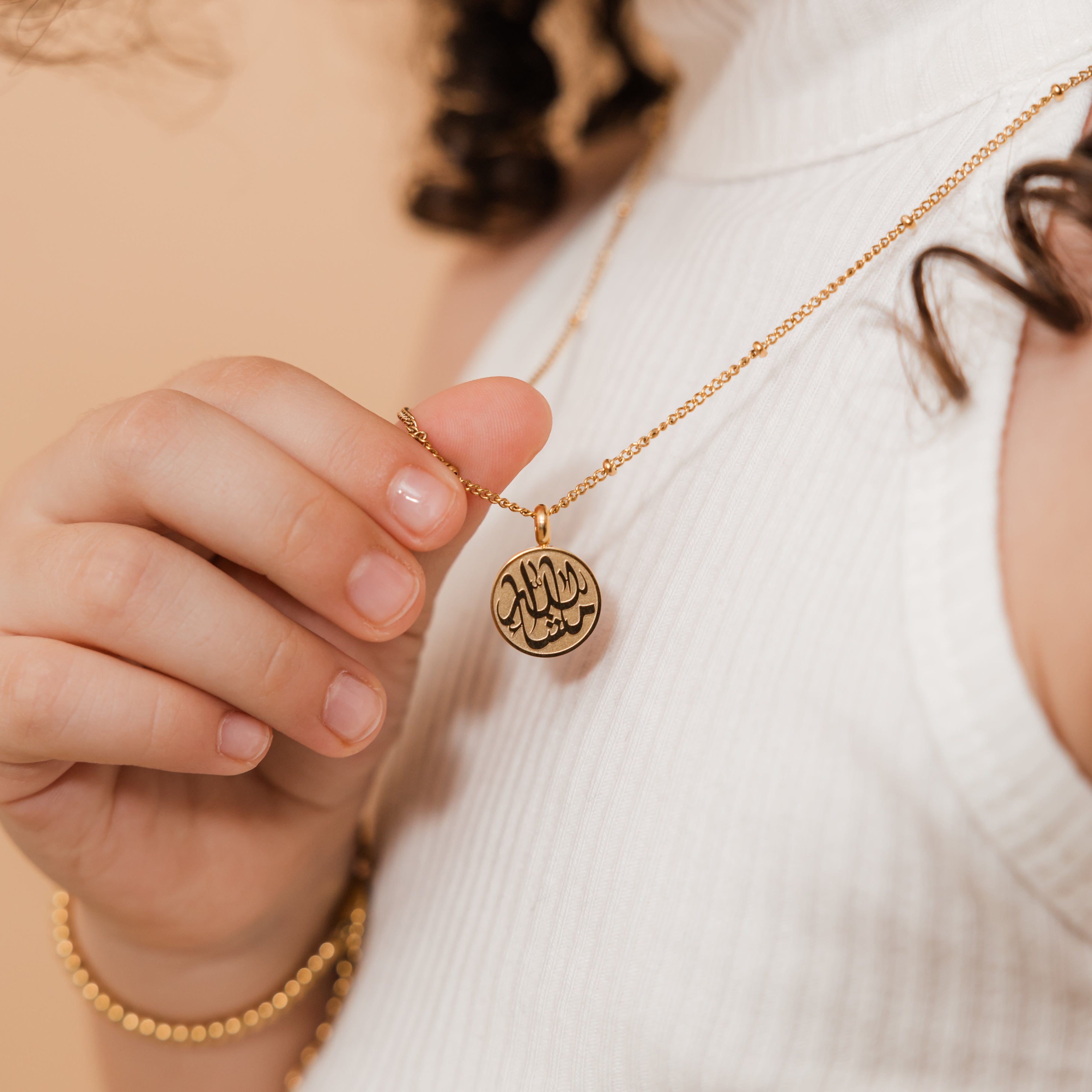 MashaAllah token necklace displayed in a velvet drawstring pouch, highlighting its gift-ready packaging.
