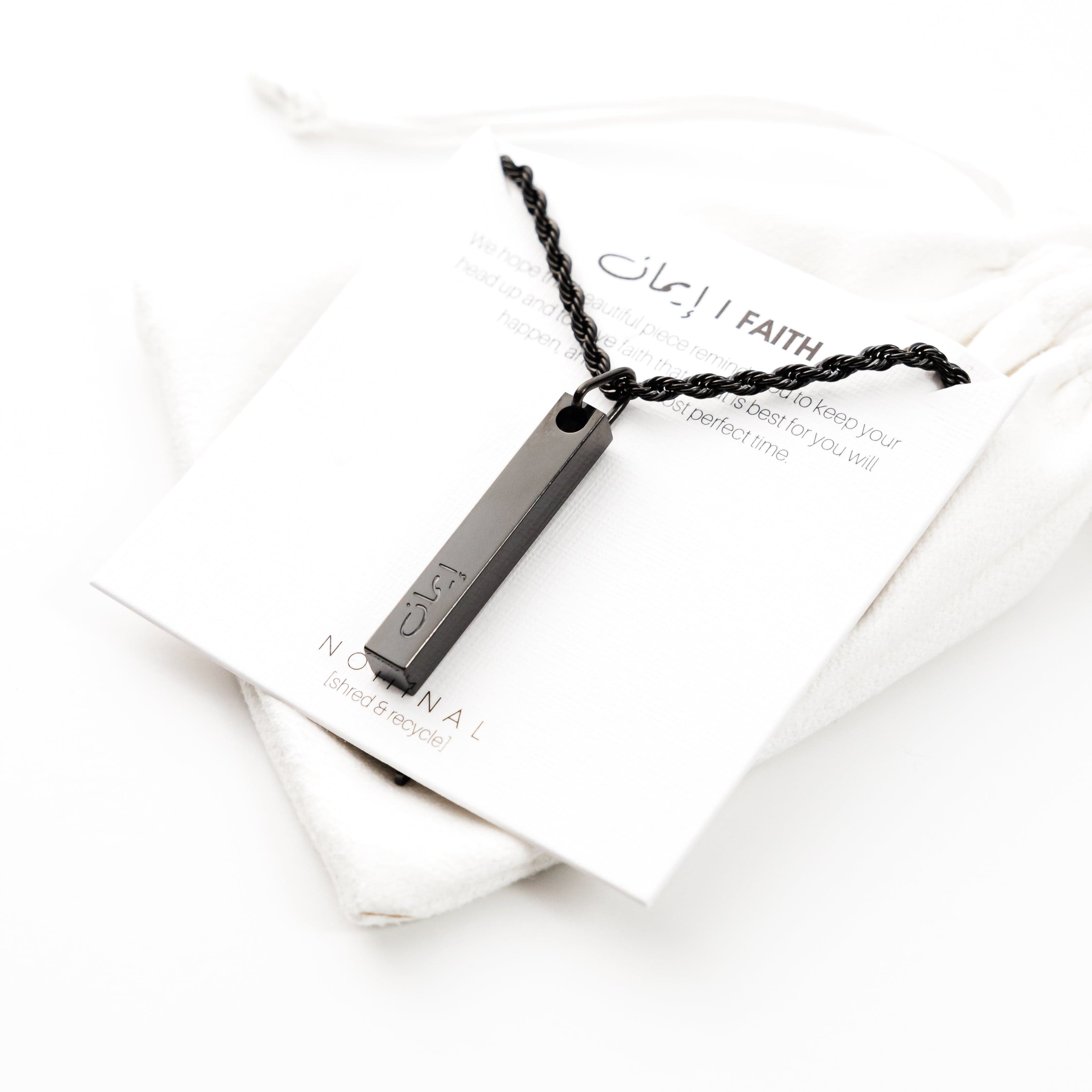 Close-up of the stainless steel pendant with faith engraved in Arabic.