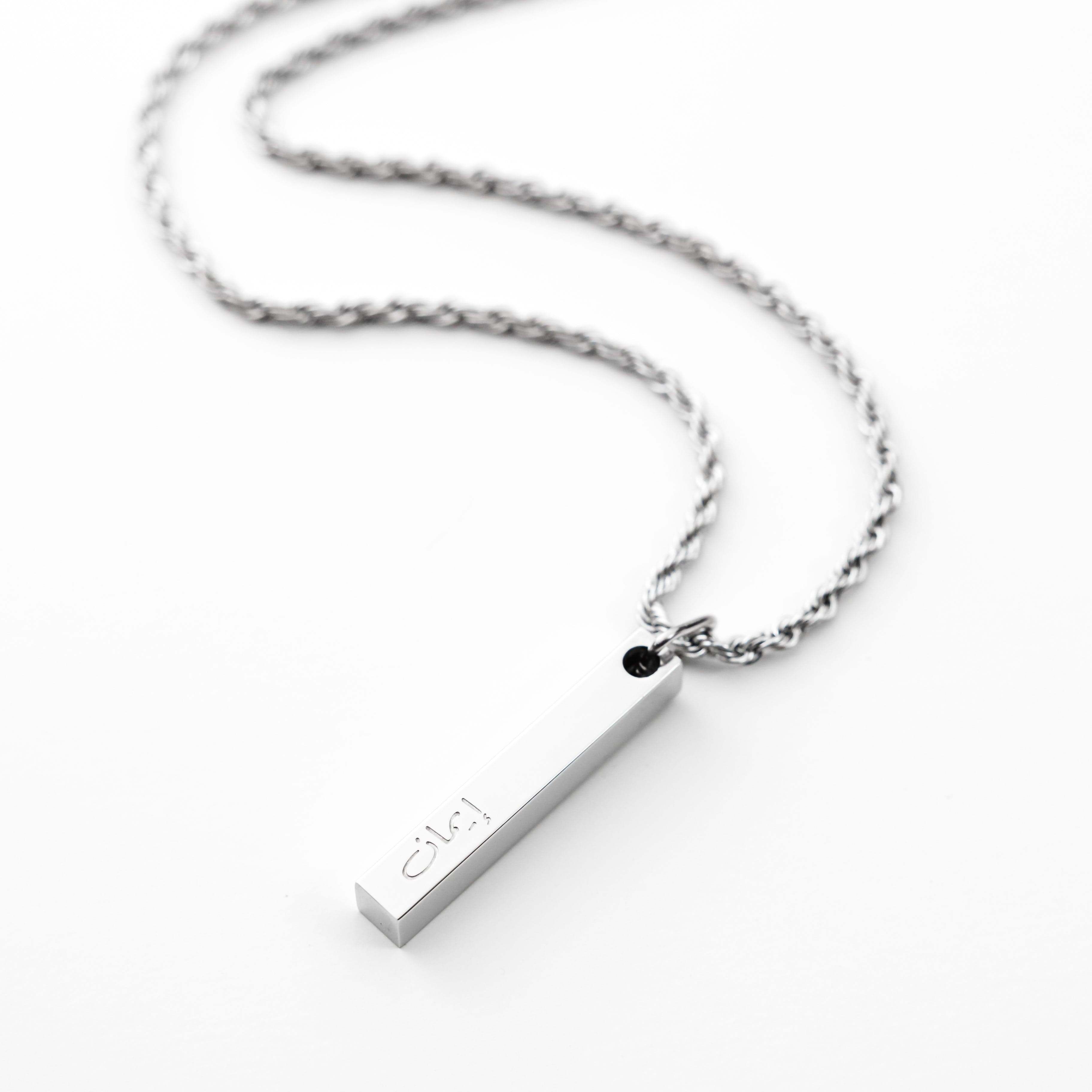 Engraved faith bar necklace for men displayed on a wooden table.