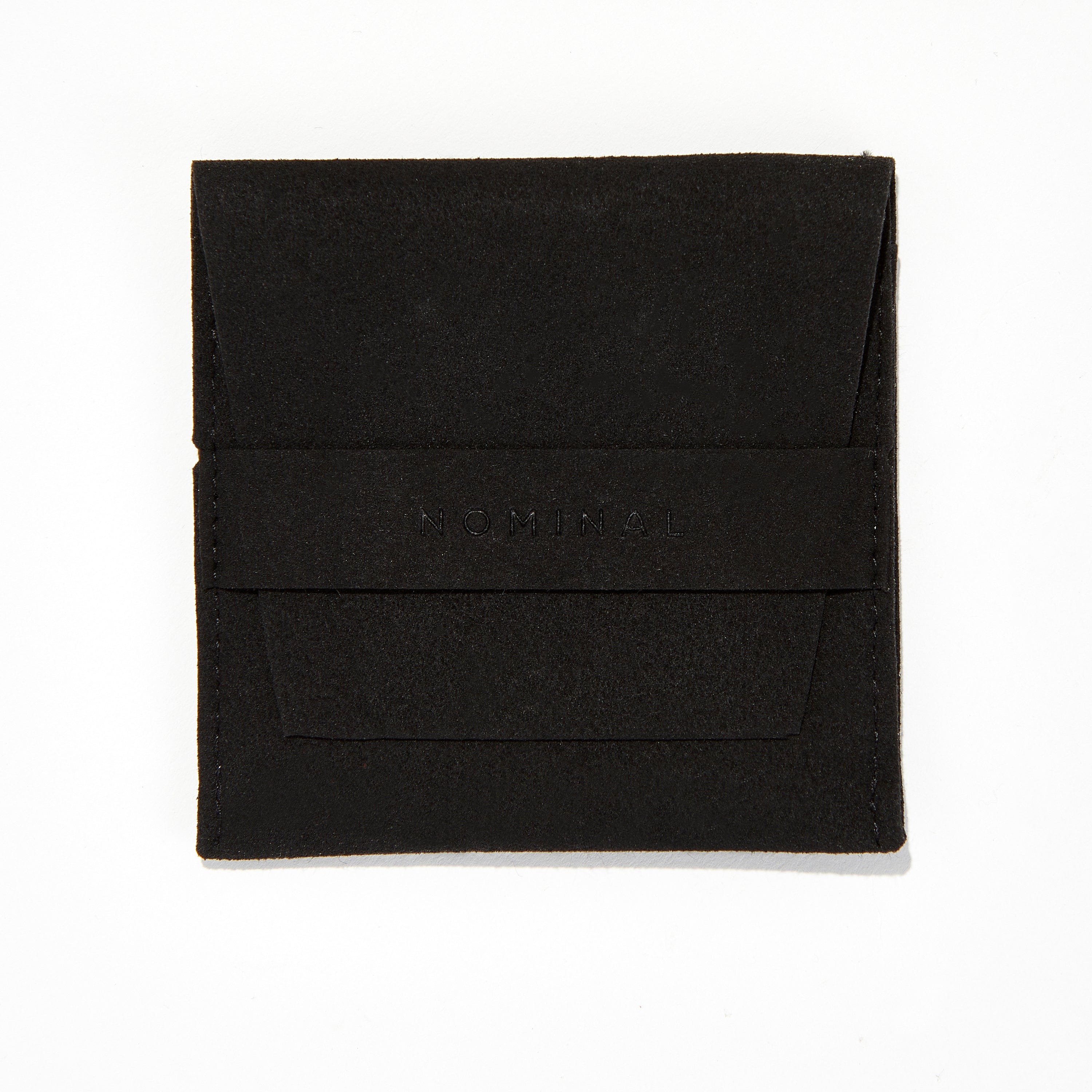 Flat lay image featuring Nominal velvet pouch next to black stacked leather bracelet
