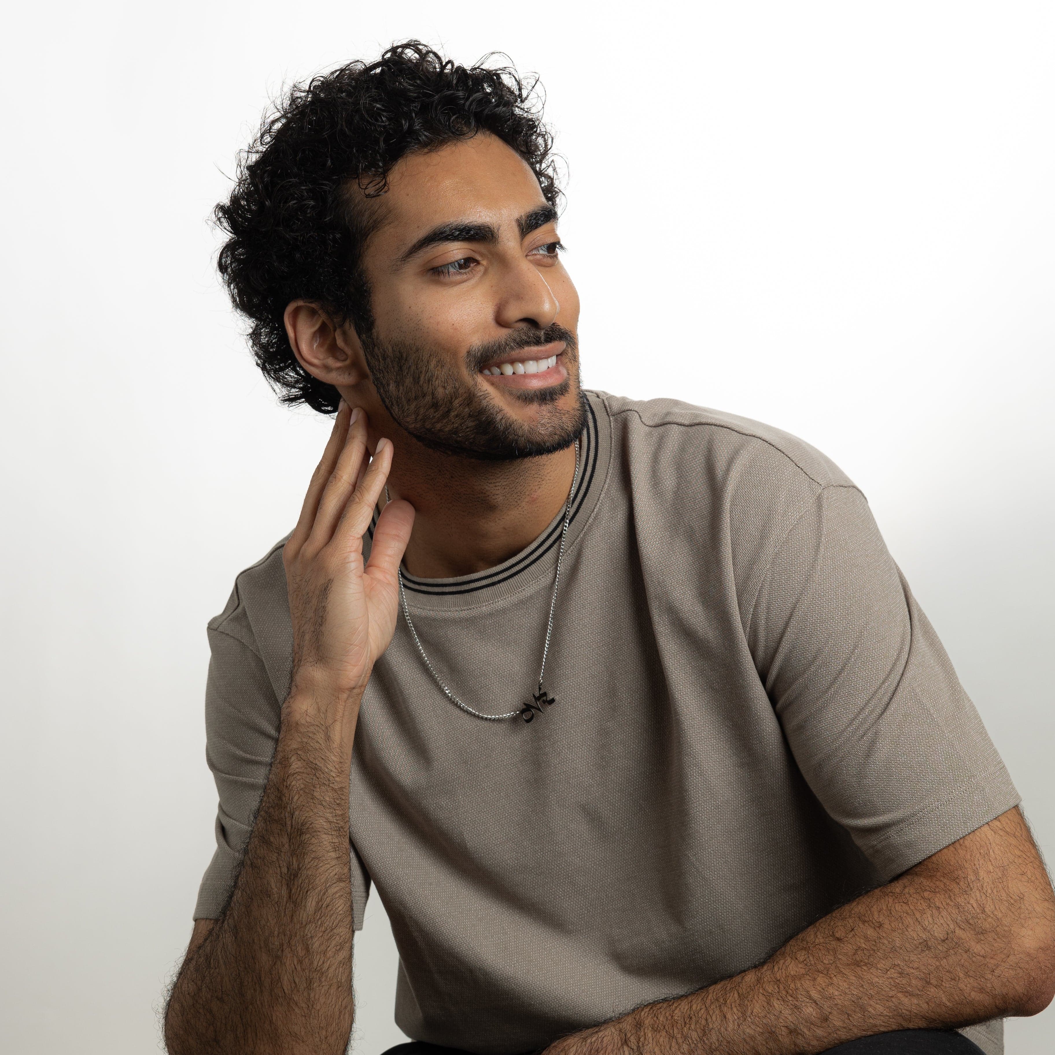 Model wearing a stainless steel necklace with a Quran verse, showcasing its everyday versatility.