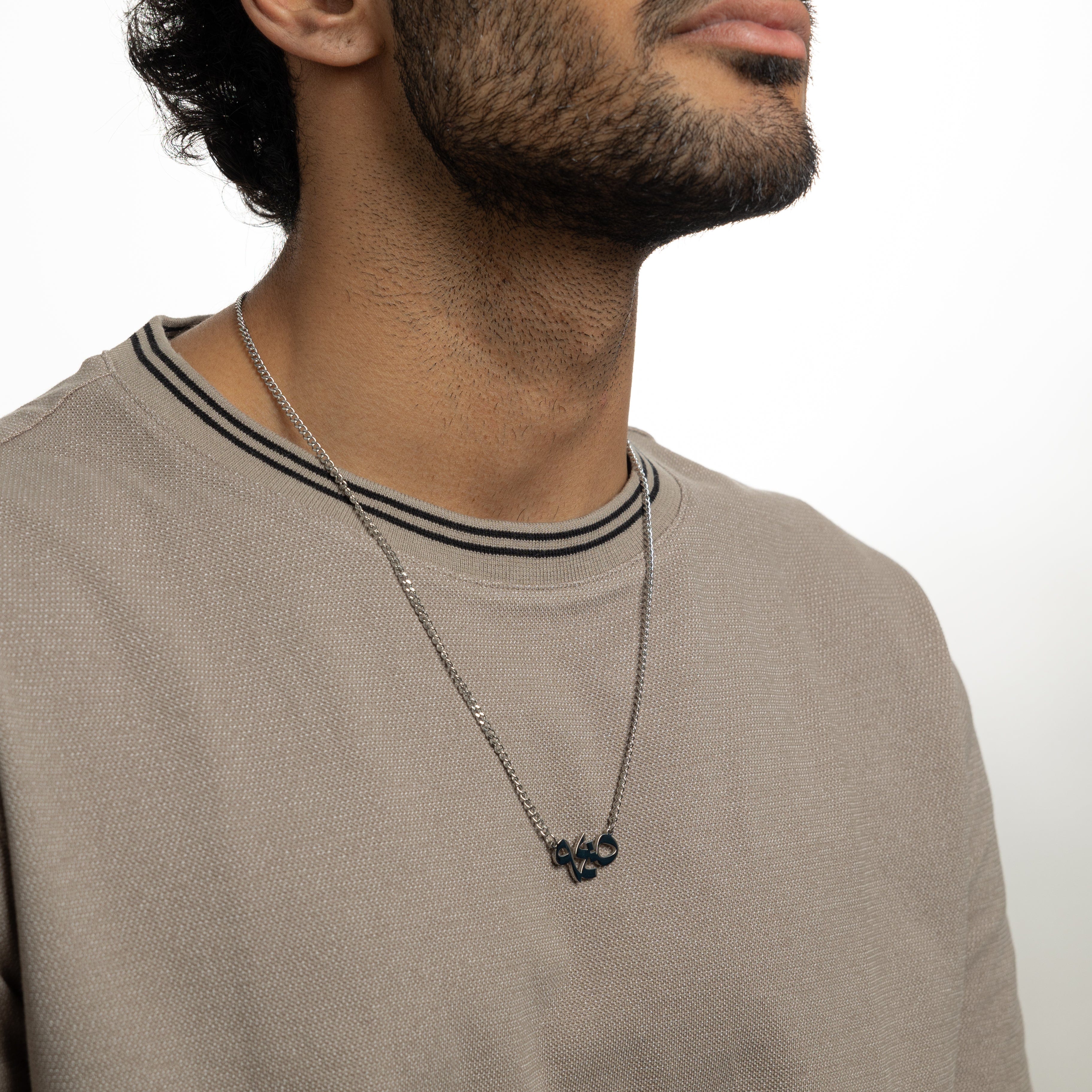 Mens stainless steel verse pendant with Arabic calligraphy showcasing With Hardship Comes Ease.