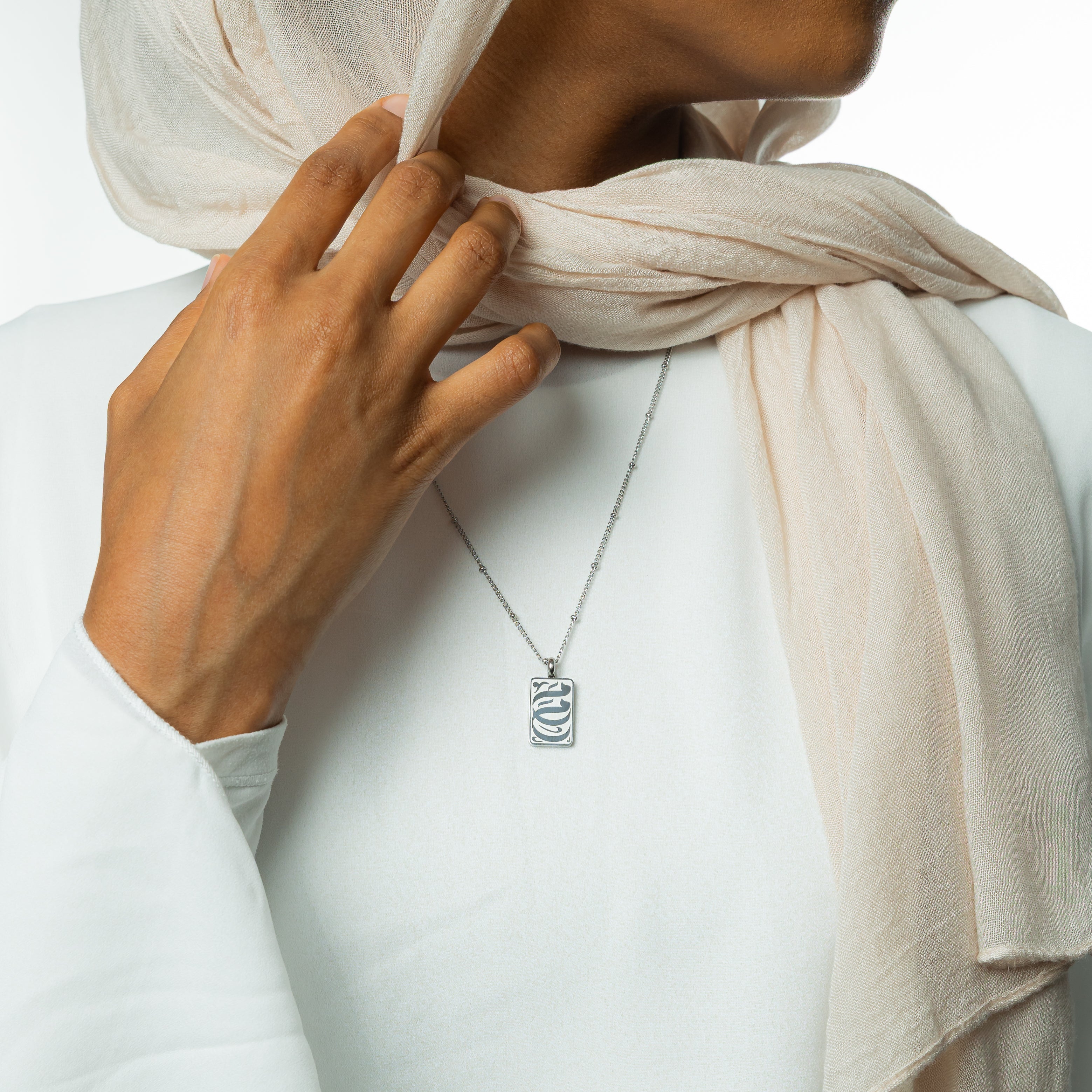 Close-up of the detailed pendant on the gold necklace that reads ummi.