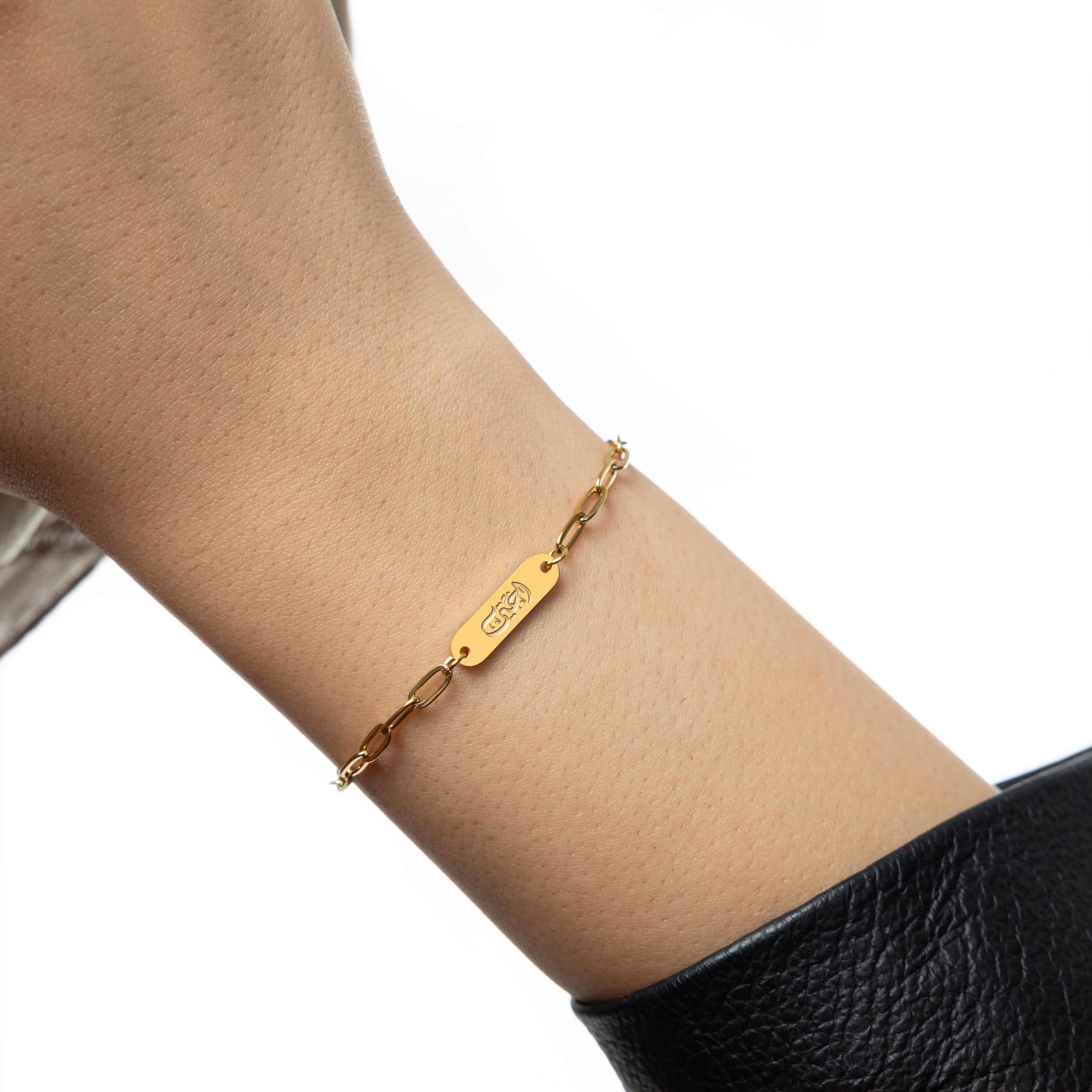 Close-up of the Ukhti link bracelet showcasing its Arabic inscription and gold finish.