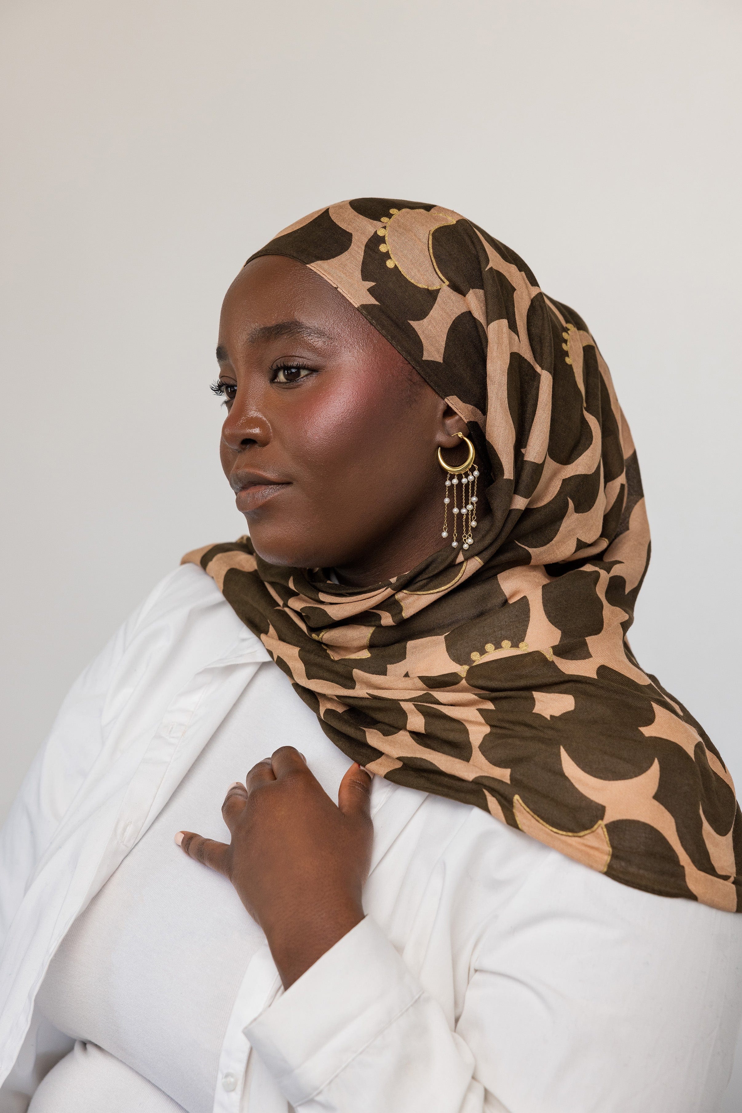 Model wearing gold hoop earrings with pearls, highlighting their elegance in a casual setting.