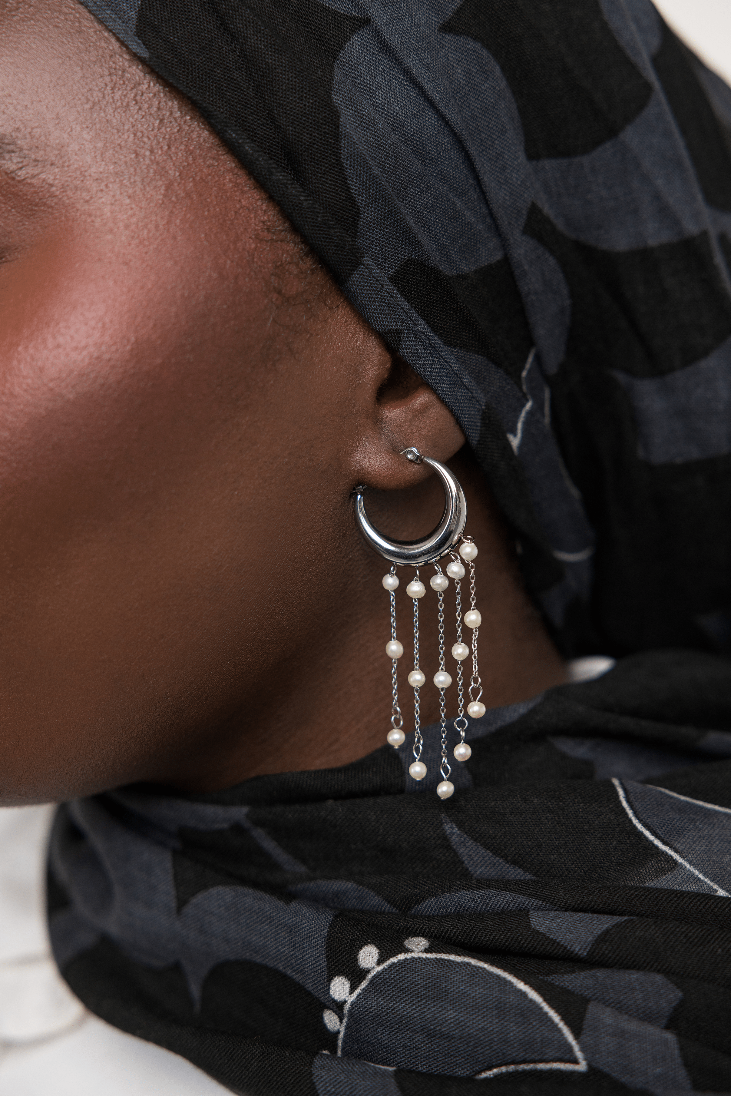 Model wearing gold hoop earrings with pearls, highlighting their elegance in a casual setting.