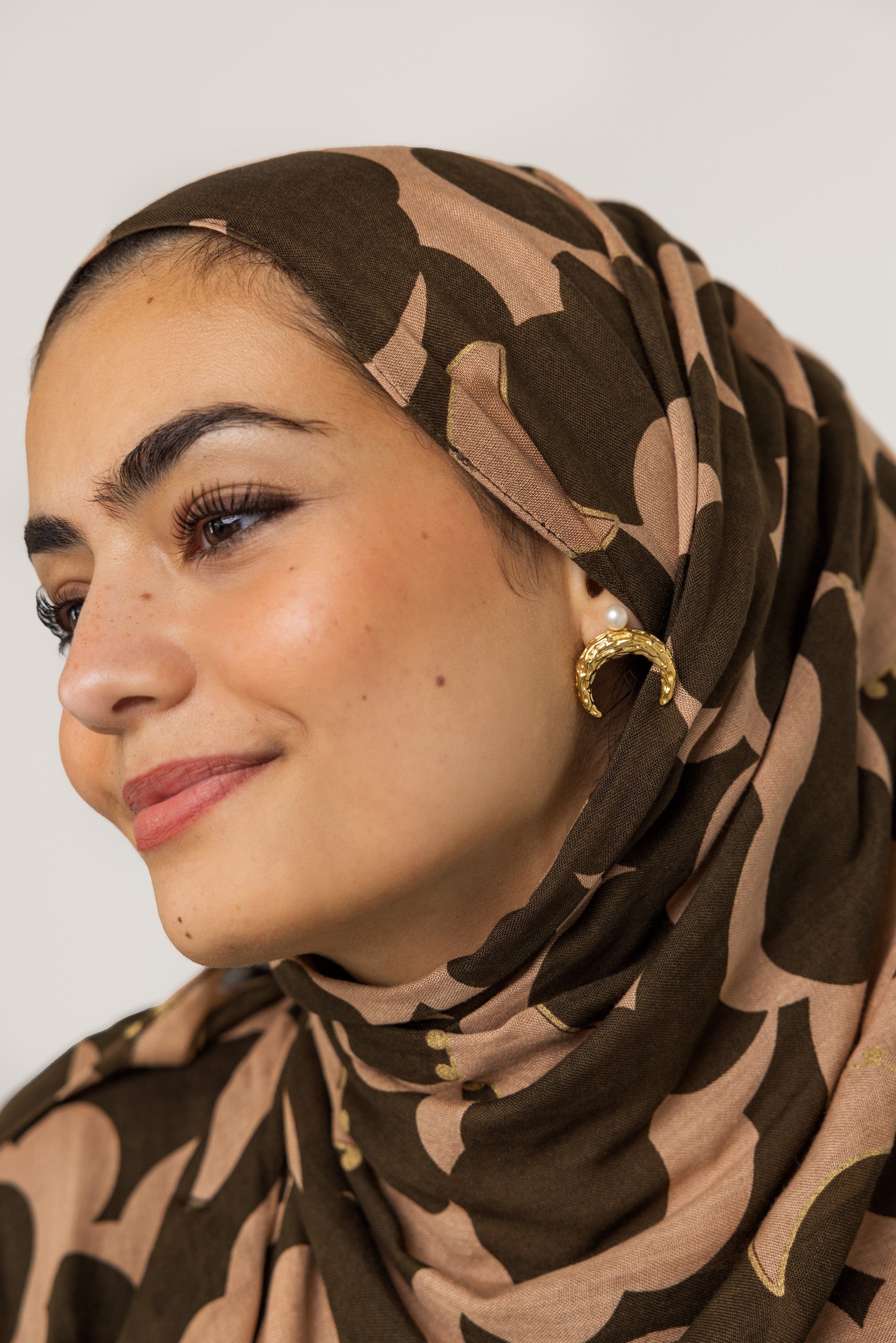 Close-up of the Cascading Pearl Crescent Earrings highlighting the hammered texture and 18K gold plating.
