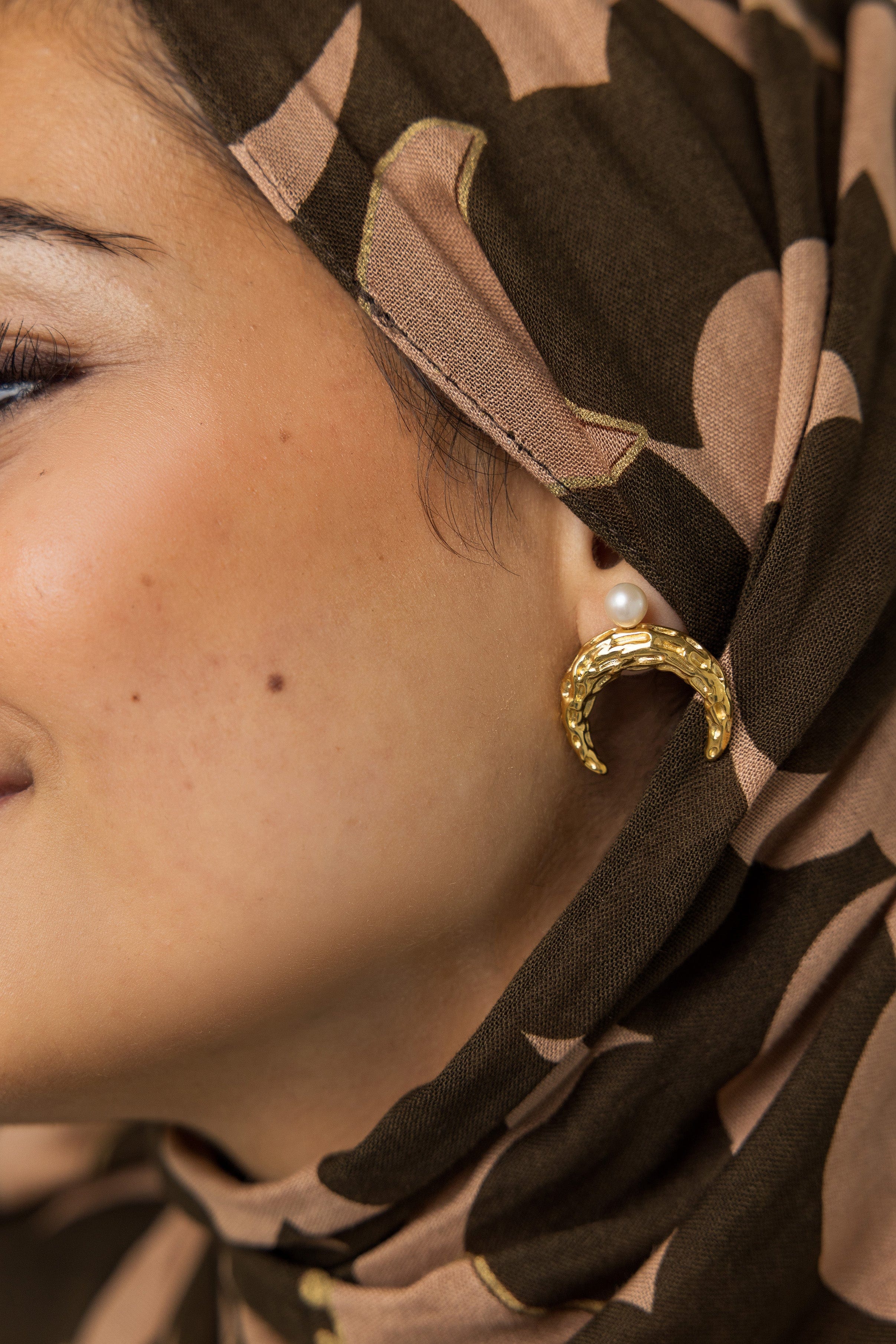 Close-up of the Cascading Pearl Crescent Earrings highlighting the hammered texture and 18K gold plating.