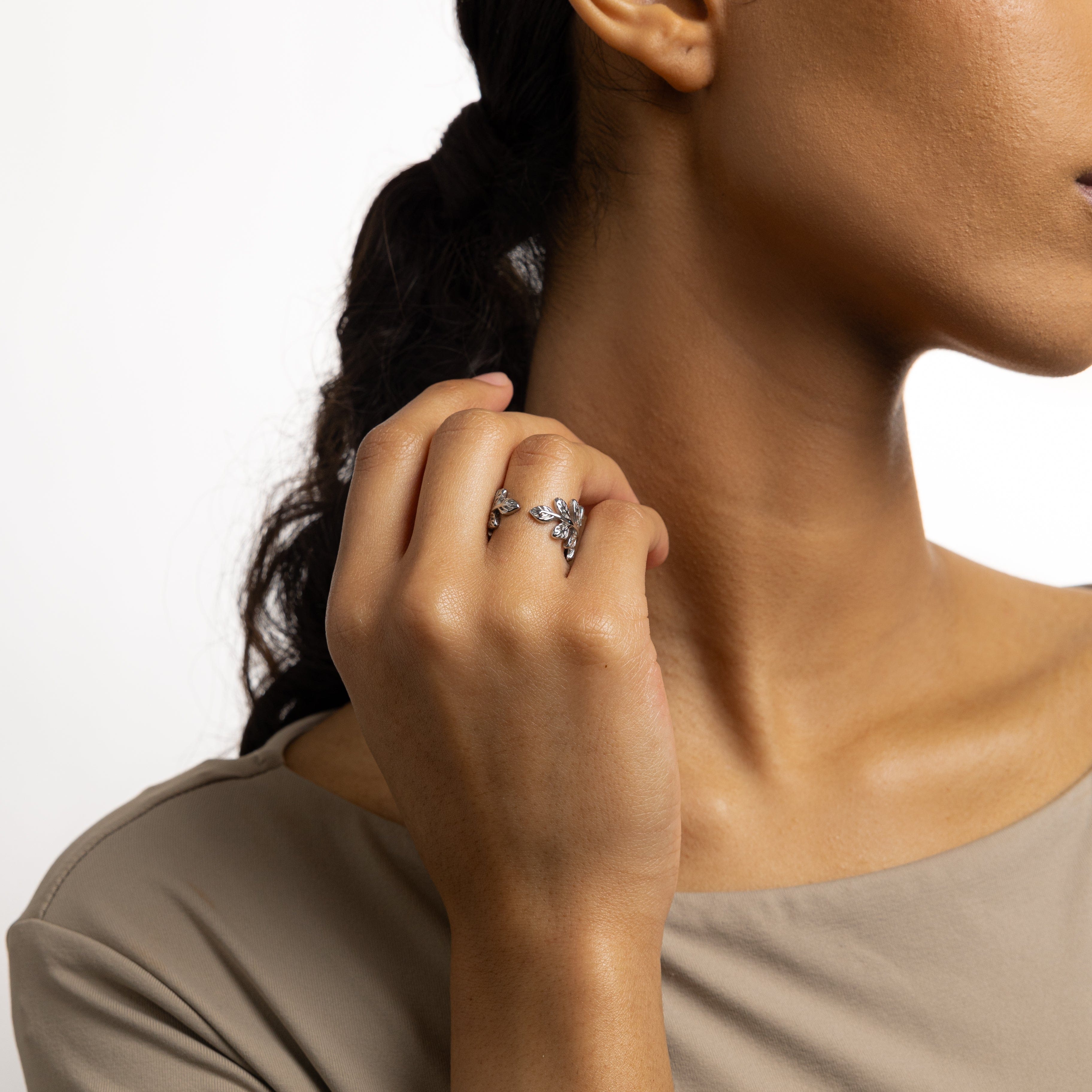 Stylish woman wearing the olive branch ring in a natural setting, representing strength and confidence.