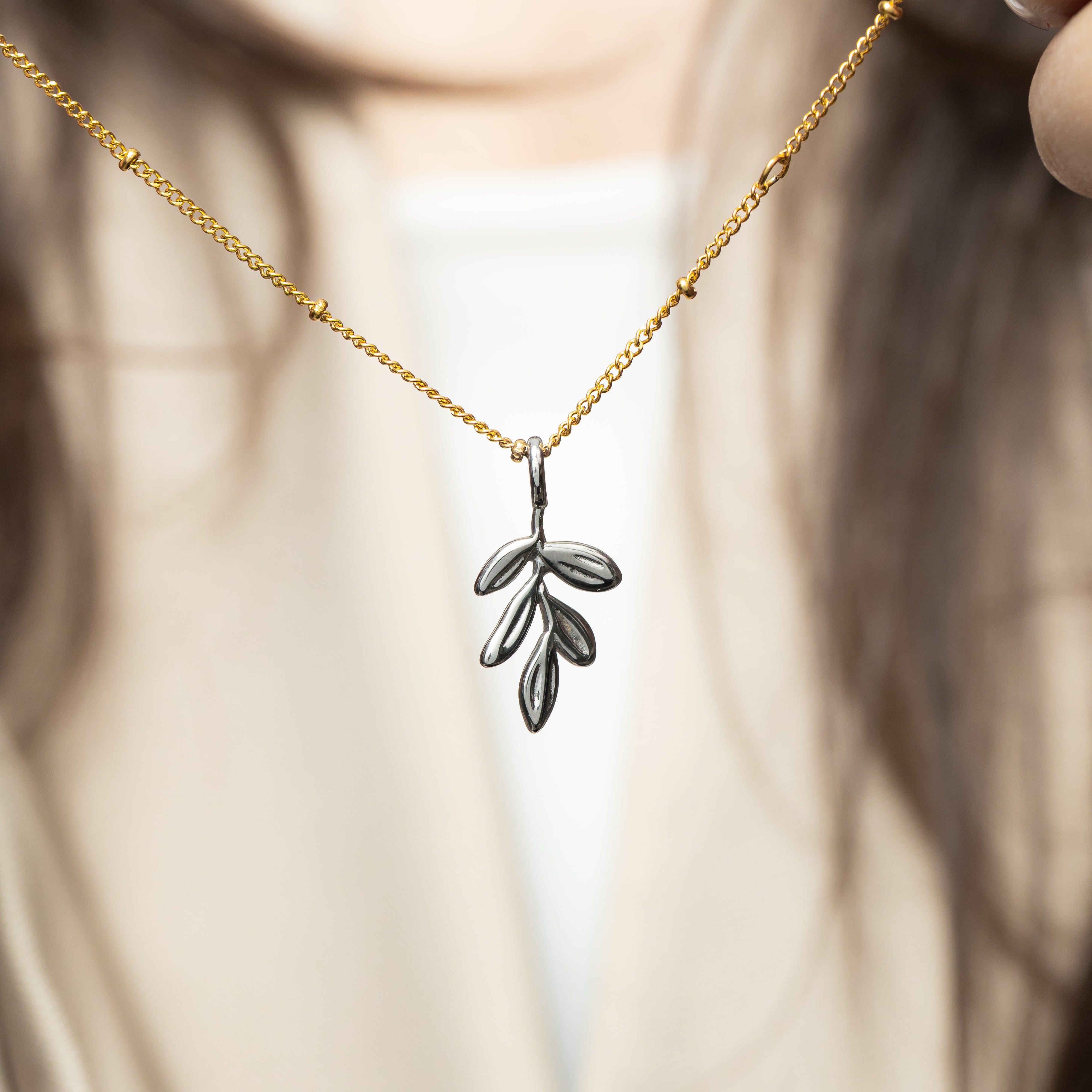 Olive branch charm displayed on a necklace, showcasing its elegance and symbolism.