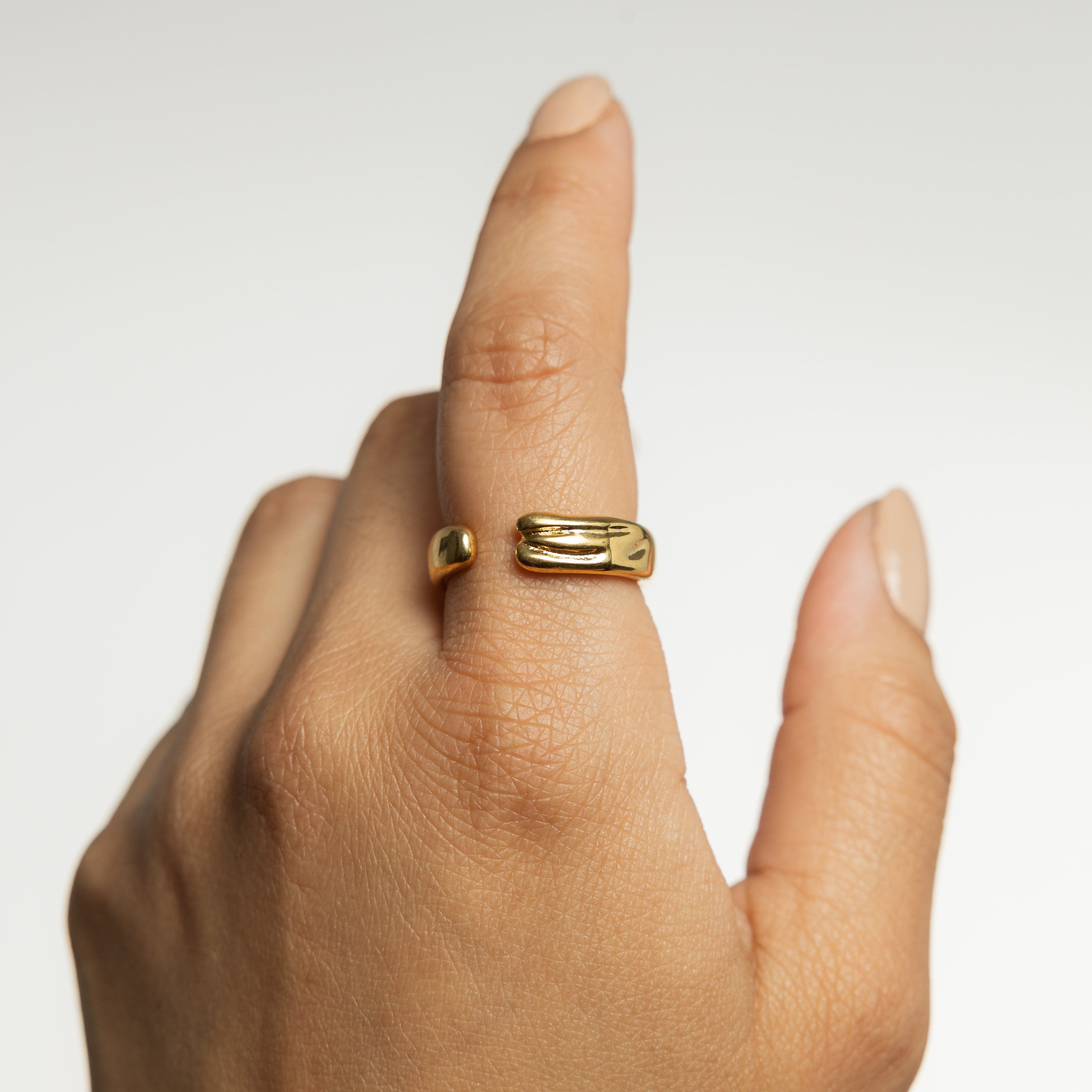 A woman wearing the Fluid Molten Gold Ring, paired with trendy stainless steel jewelry for a chic look.
