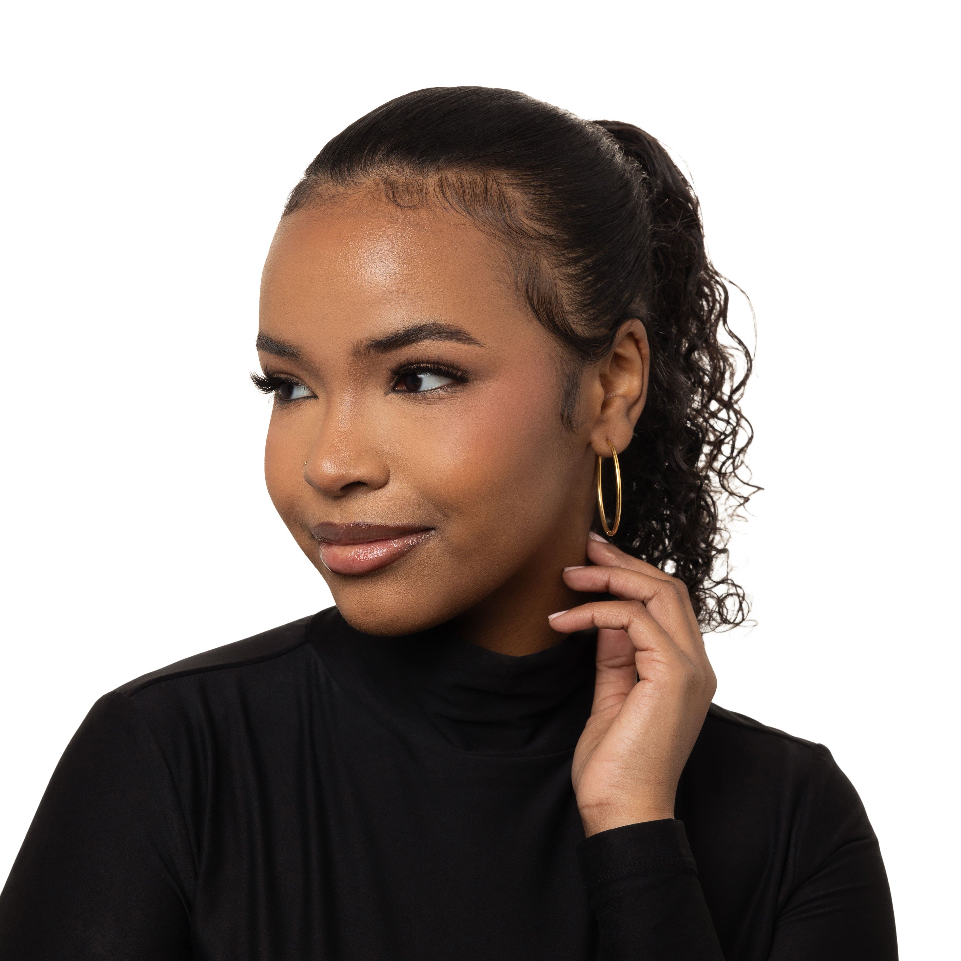 Close-up of bold 40mm gold hoop earrings showcasing the shine and details.