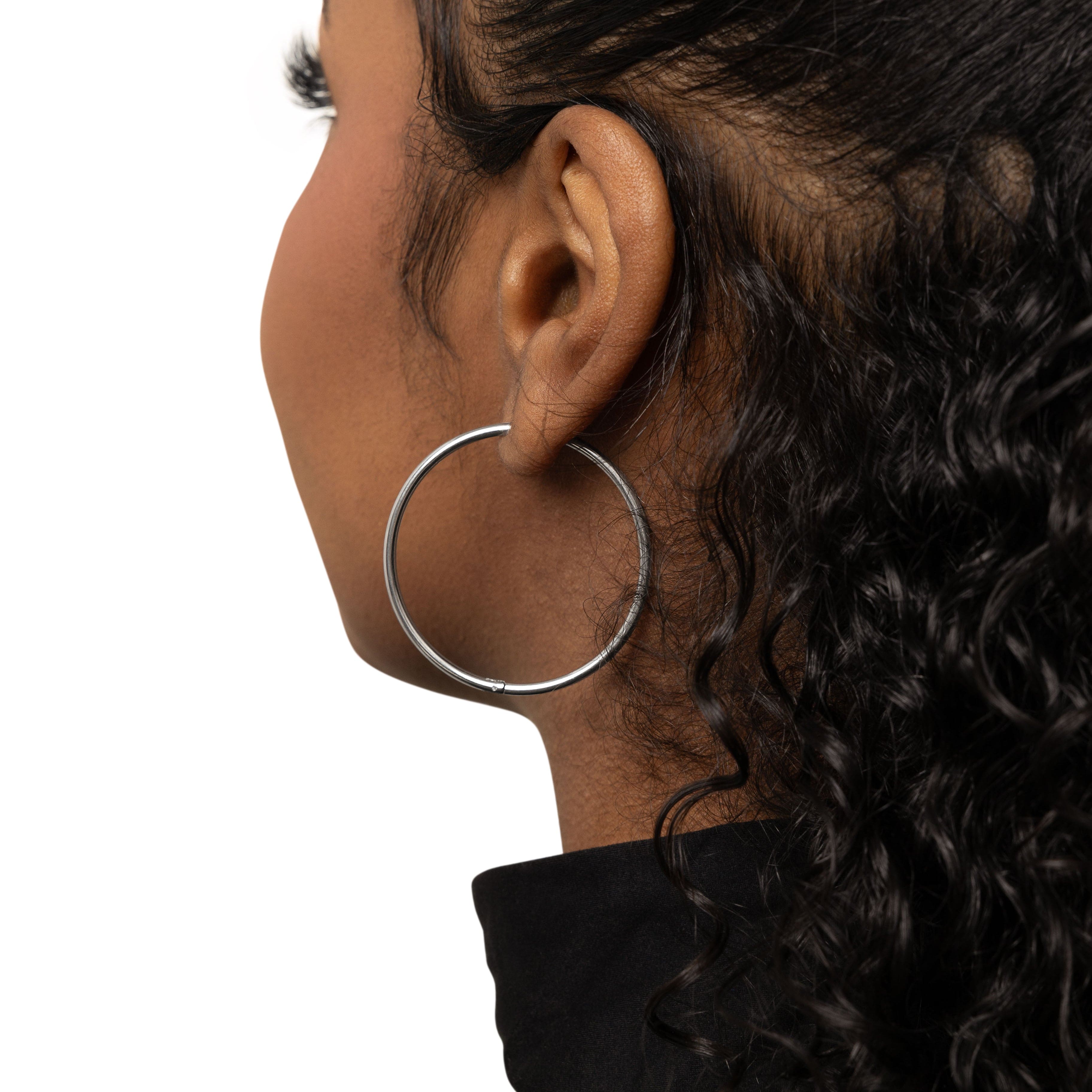 Close-up of bold 40mm gold hoop earrings showcasing the shine and details.