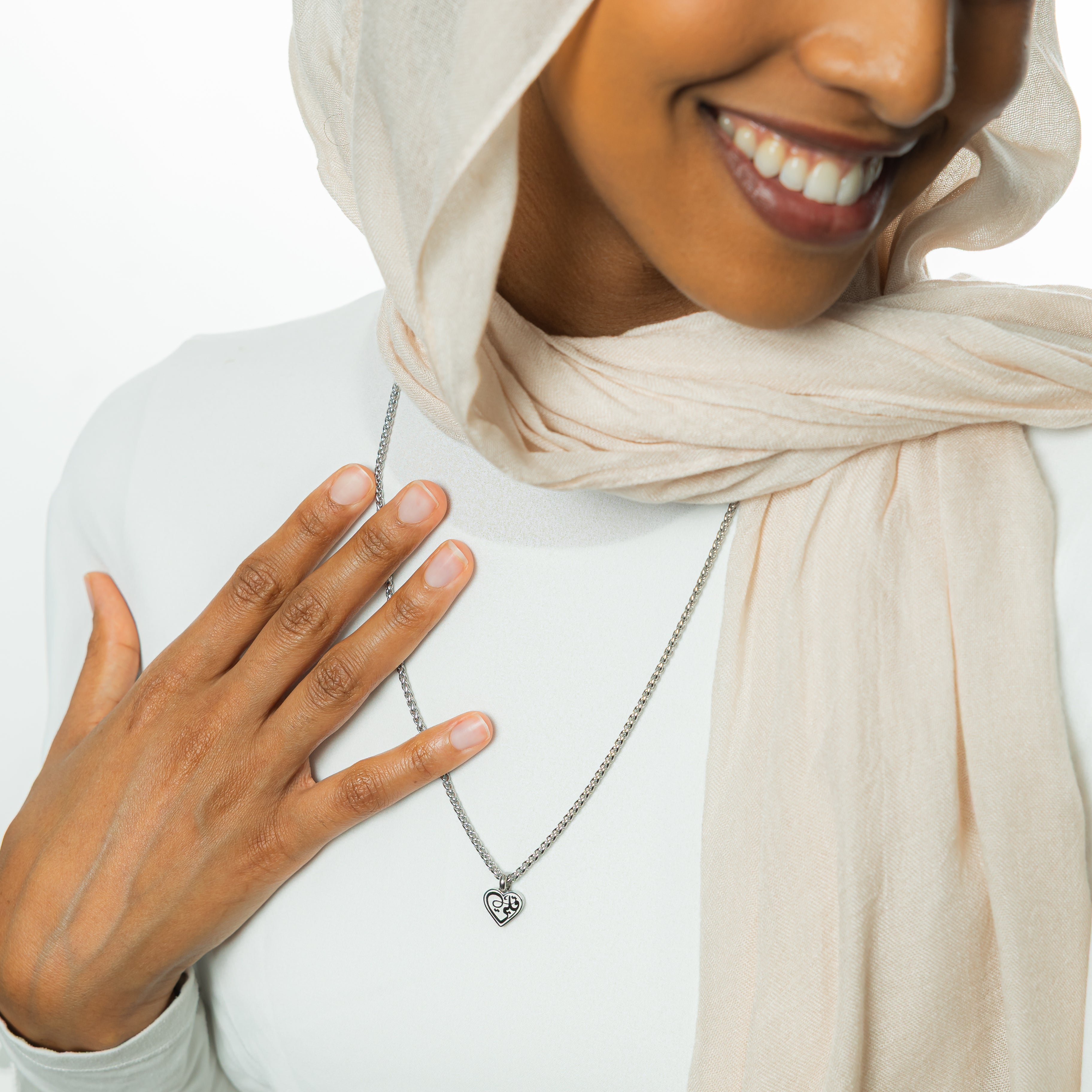 Close-up of the gold heart necklace for sensitive skin with Arabic calligraphy.