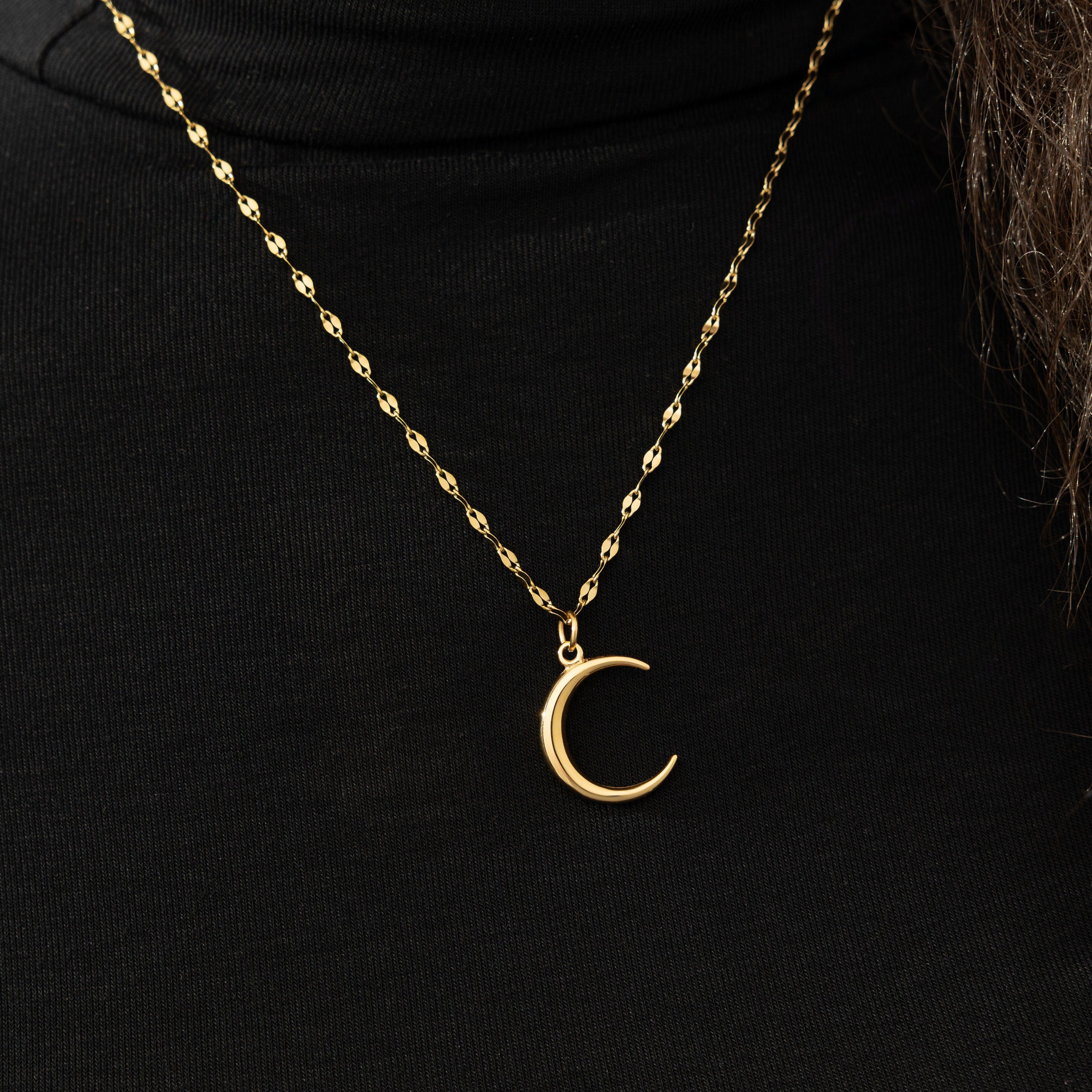 Close-up of the crescent necklace on a models neck, demonstrating its stacking style with other jewelry.
