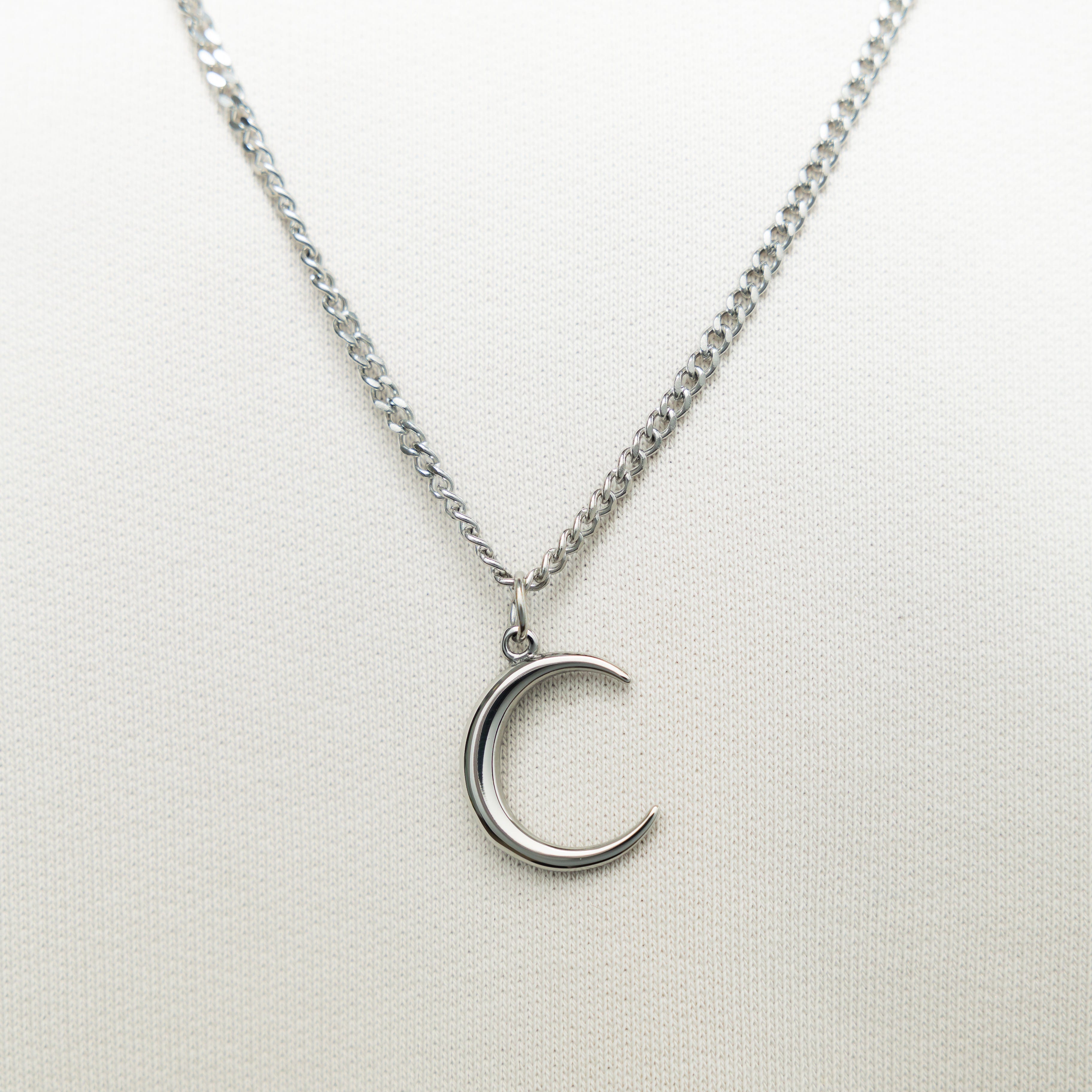 Close-up of the stainless steel crescent pendant highlighting its 3D design.