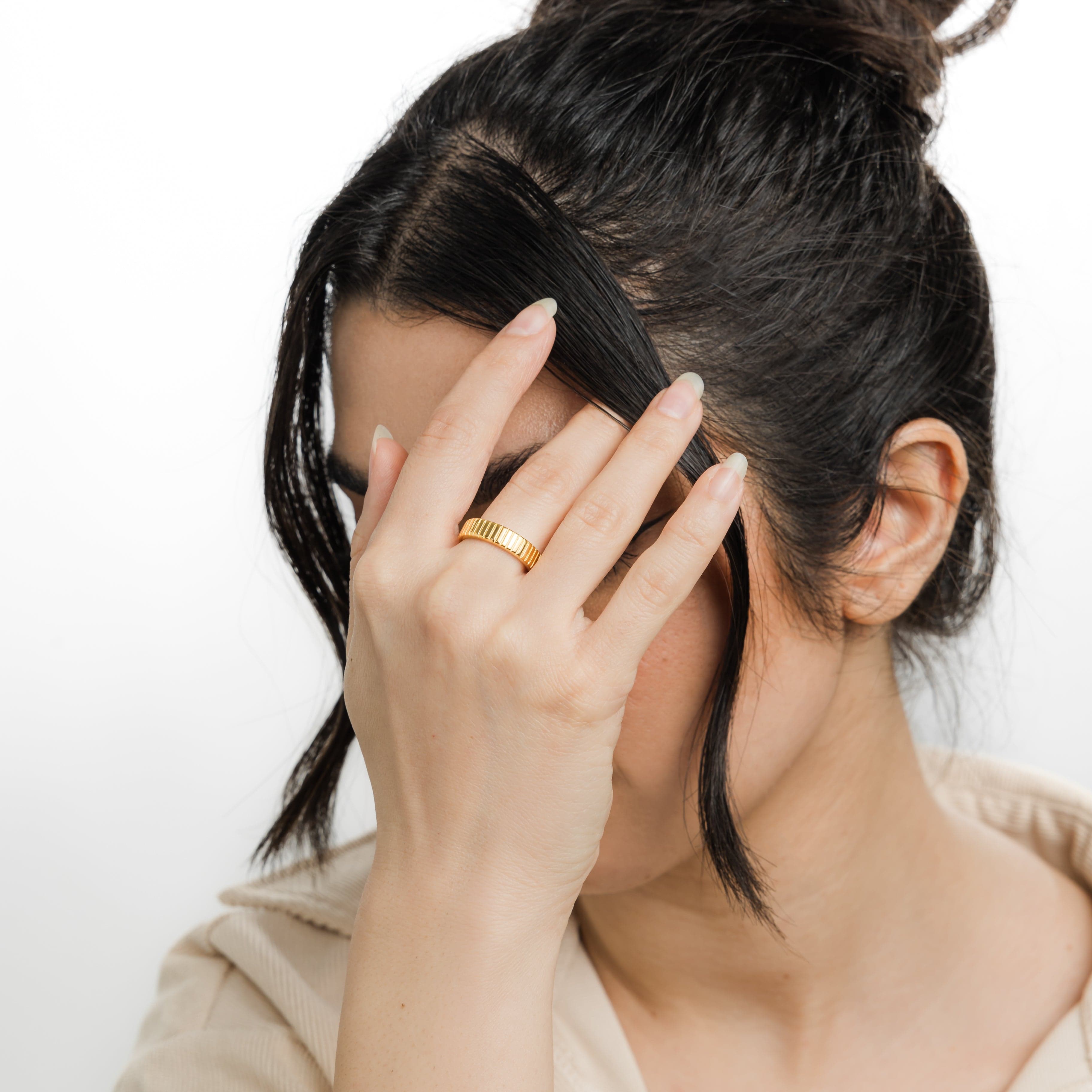 Velare™ Ridged Ring stacked with other gold rings on a model’s hand, showcasing depth and texture