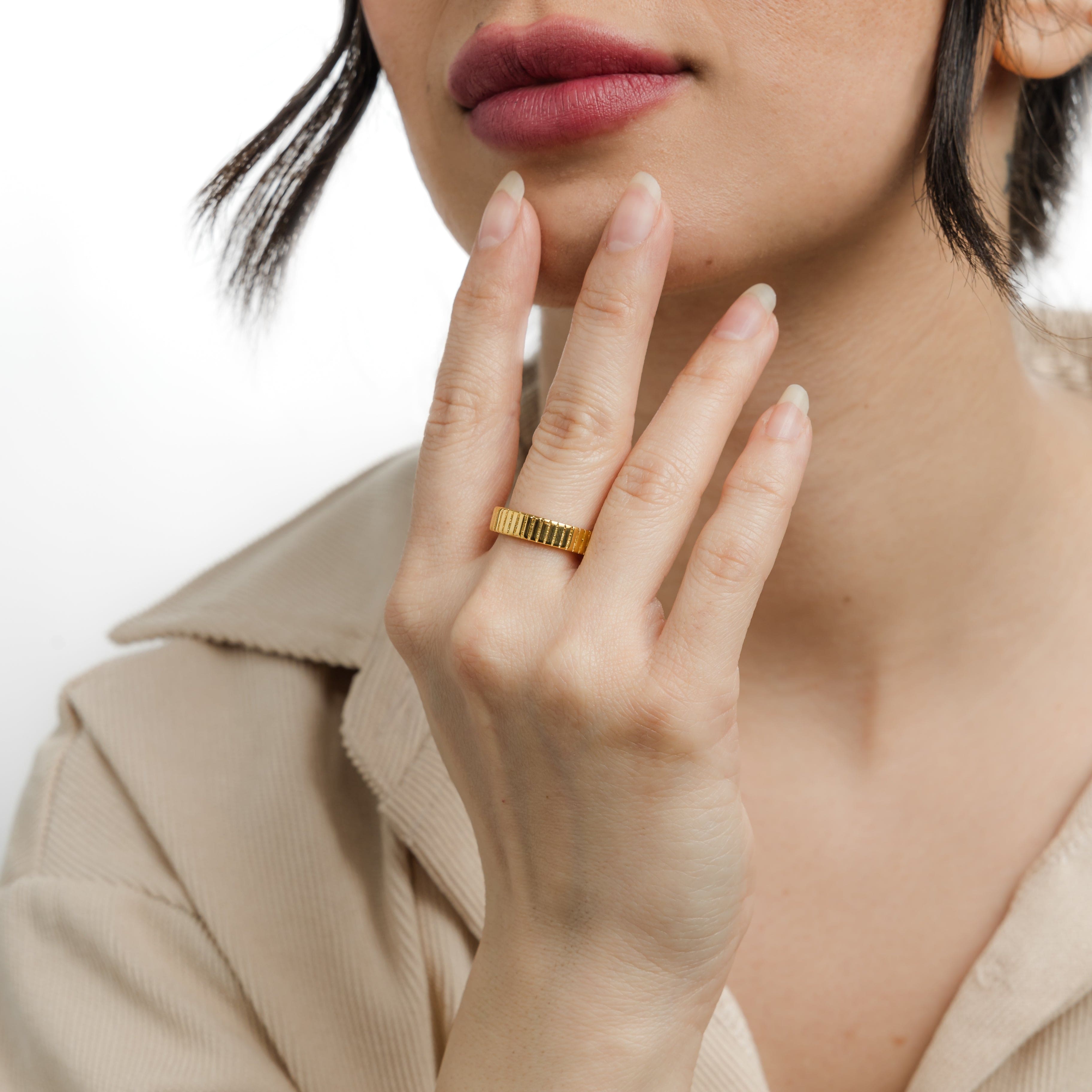 Close-up of ridged ring showing 18K gold finish and vertical grooves for visual impact