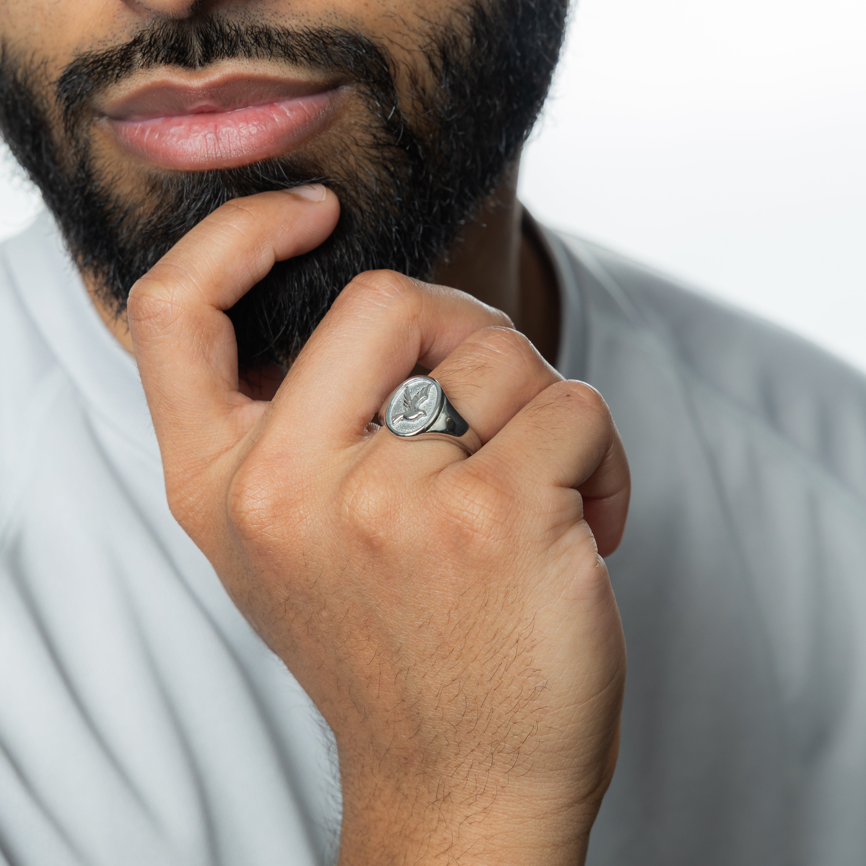 Angled photo of stainless steel mens ring next to velvet packaging pouch