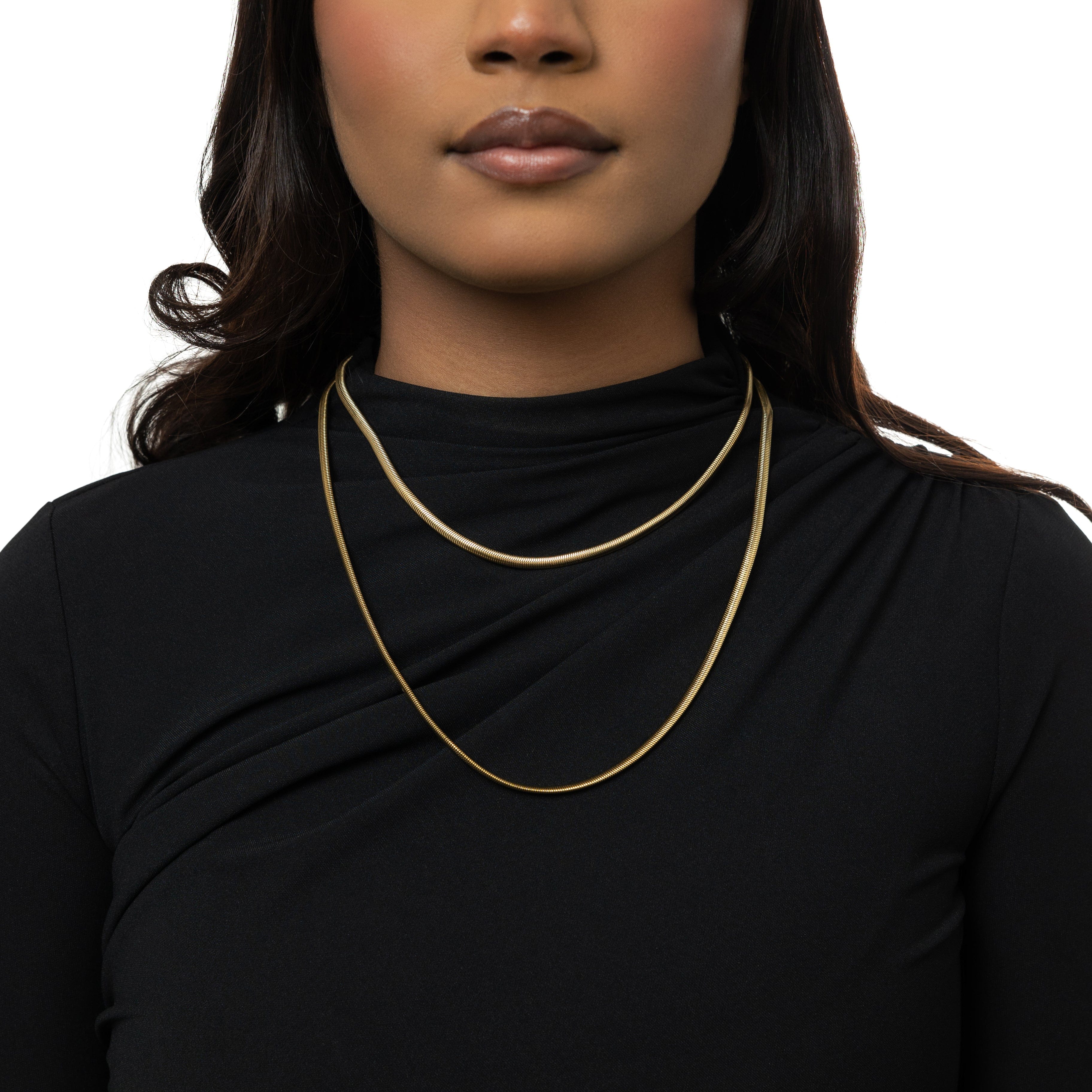 Model wearing the gold snake chain anklet at a beach, highlighting its waterproof feature.