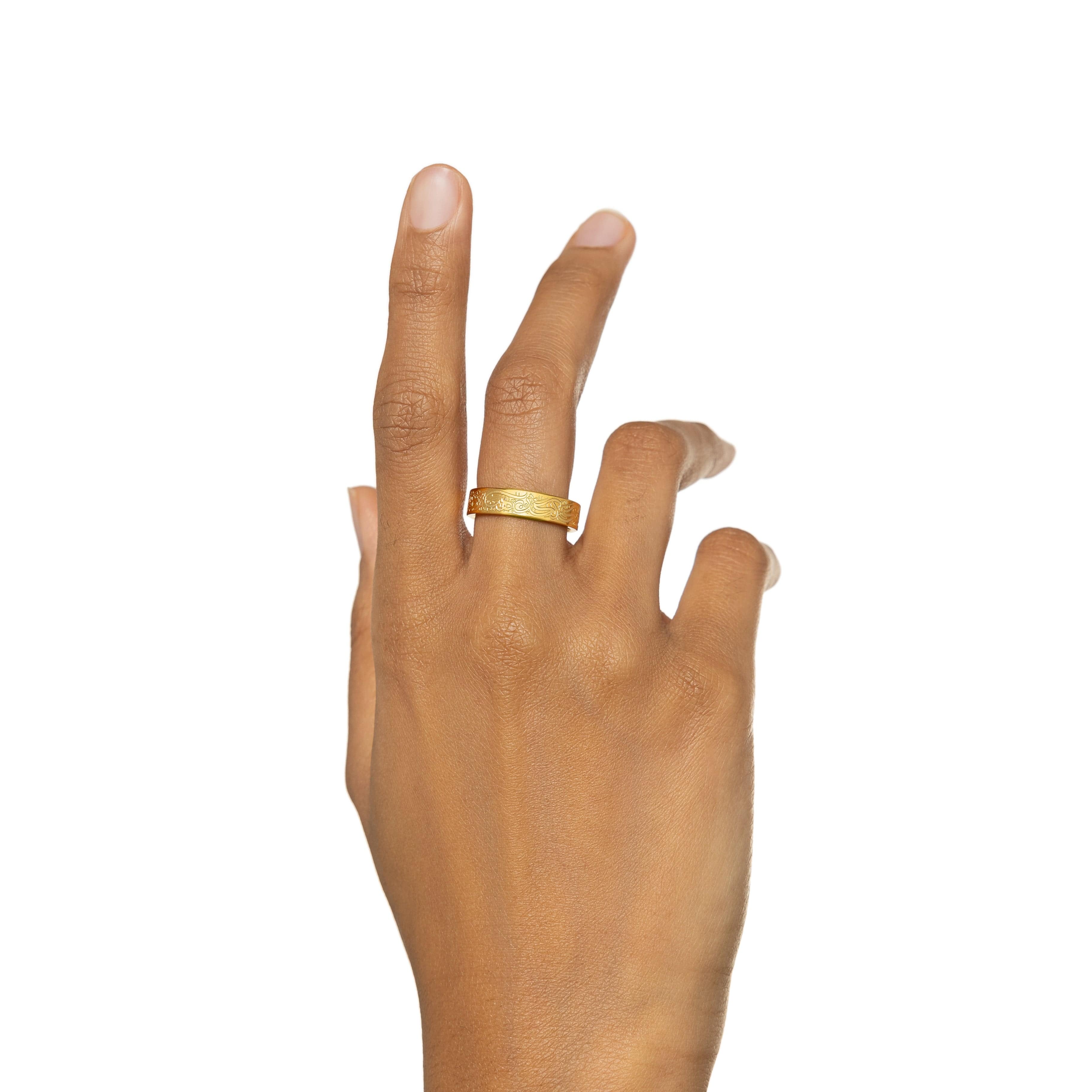 Close-up of the gold plated resilience ring with quote, showing detailed engraving on the outer band.