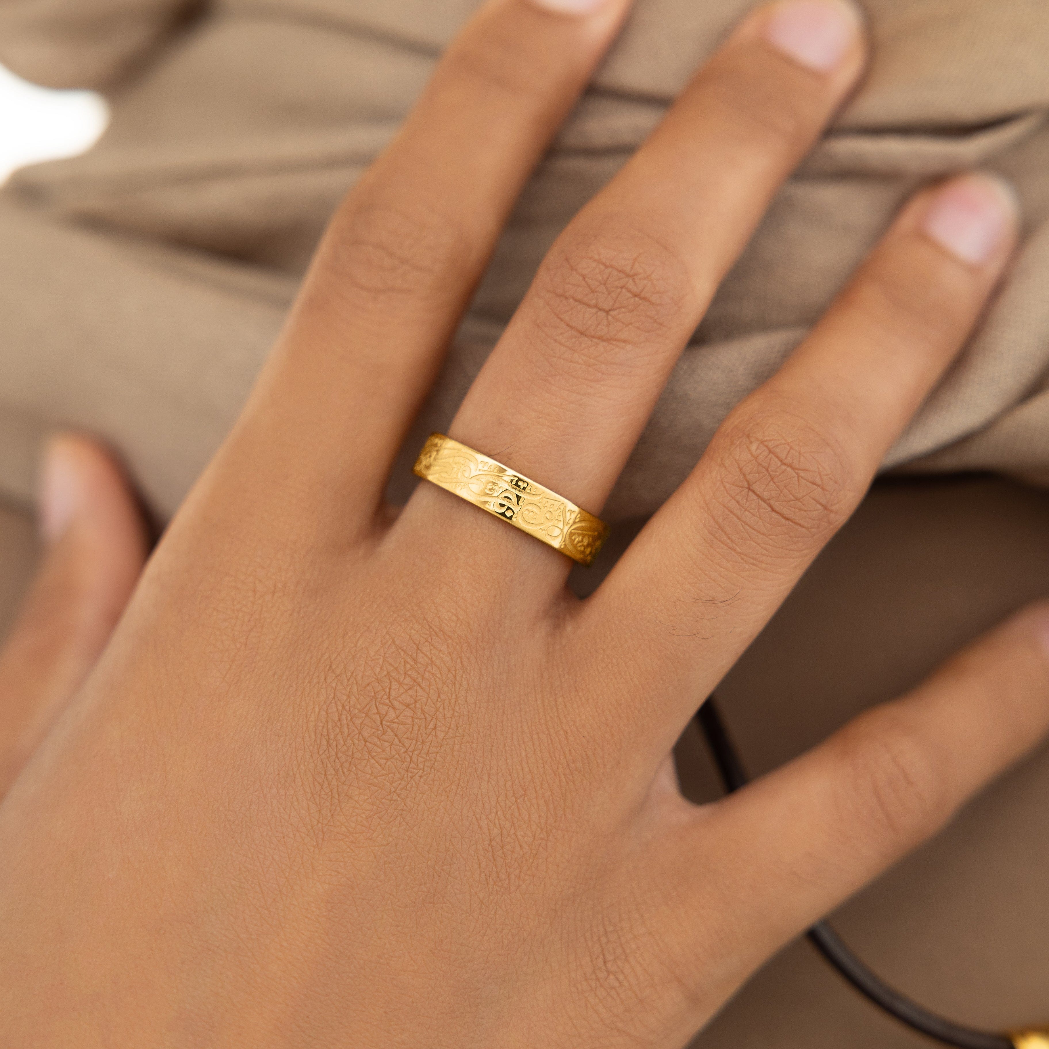 Close-up of Rumis inspirational ring showing the inscription and gold plating.