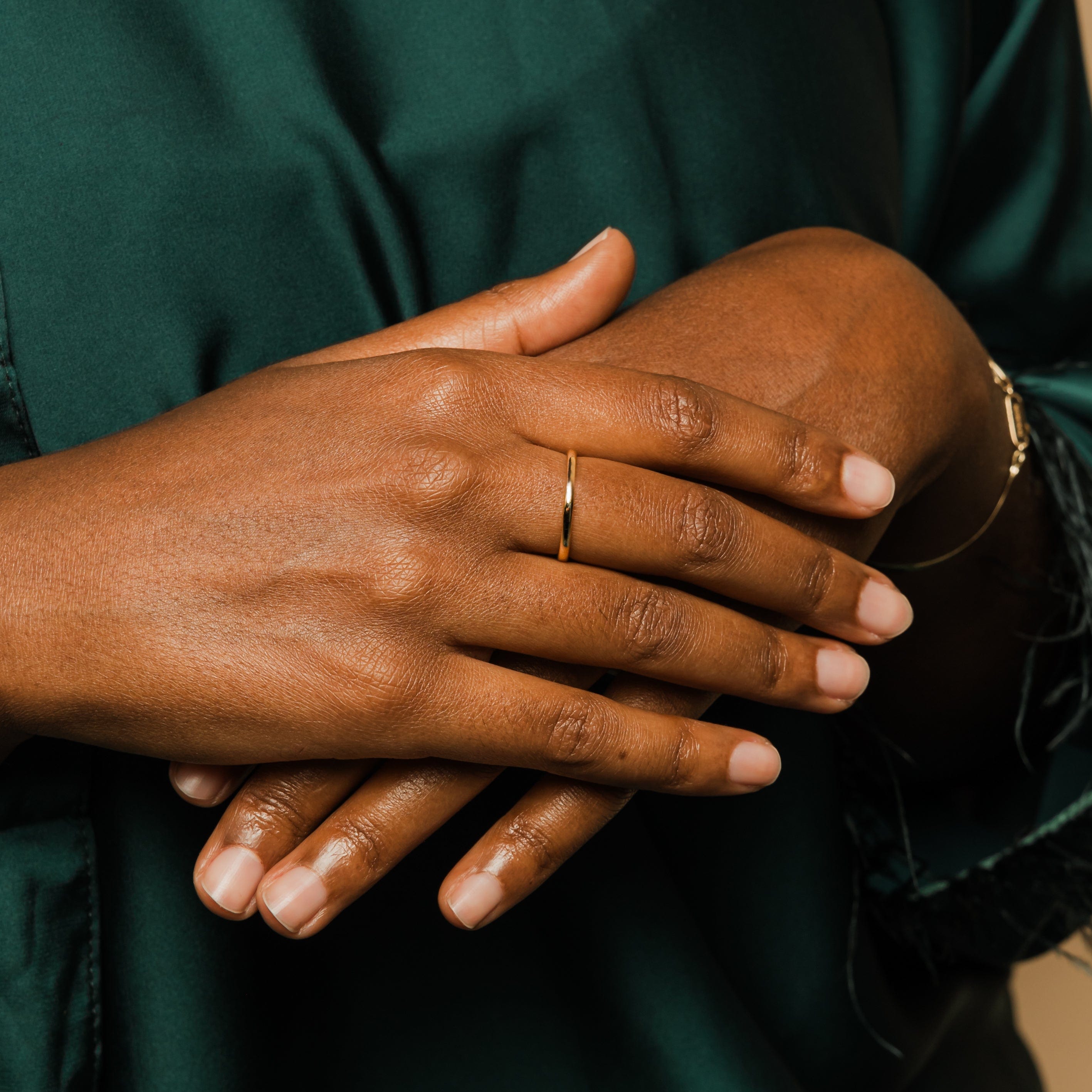 Lifestyle shot of the minimalist gold ring stacked with other thin band rings, demonstrating versatility.