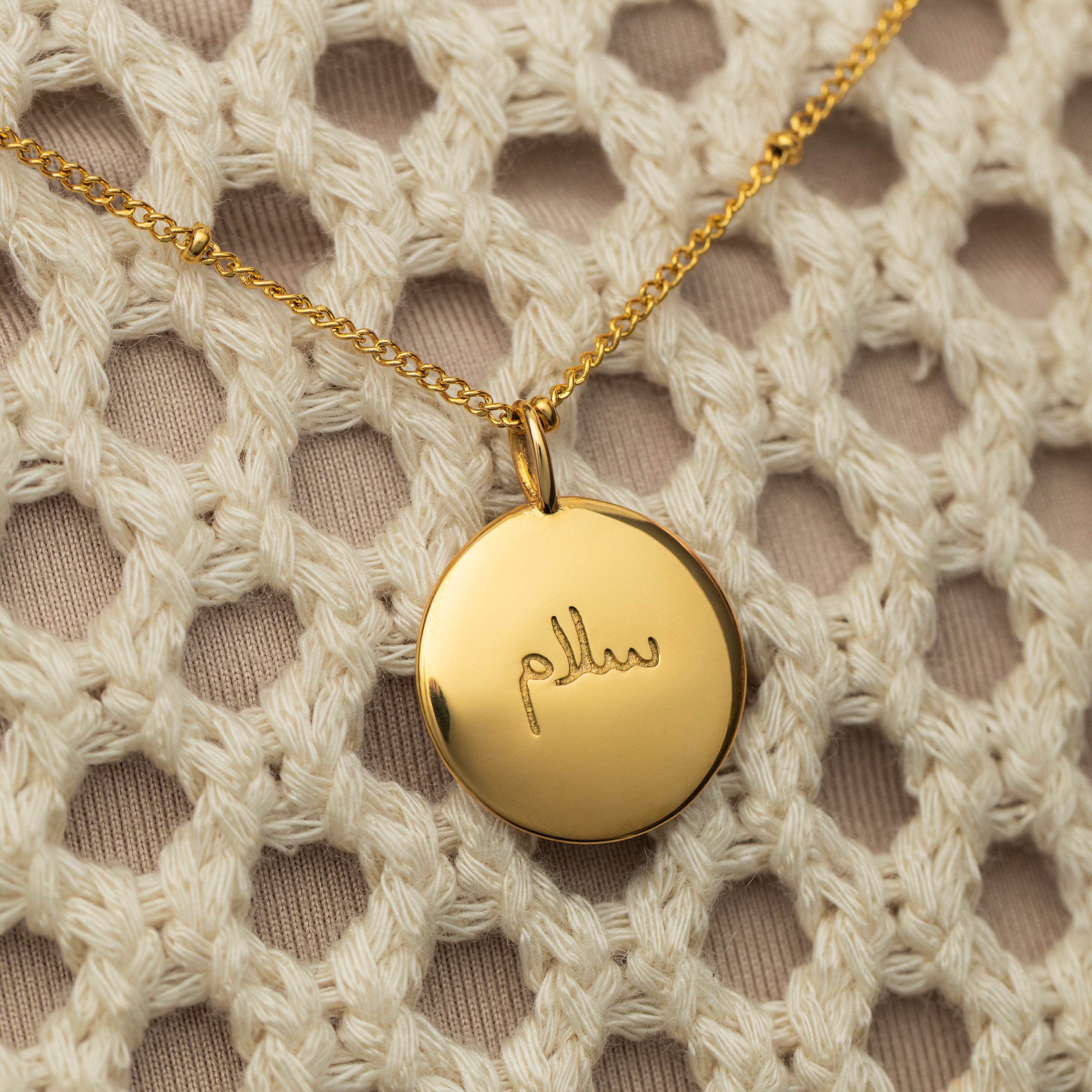 Serenity Gold Charm with Arabic engraving showing peace.
