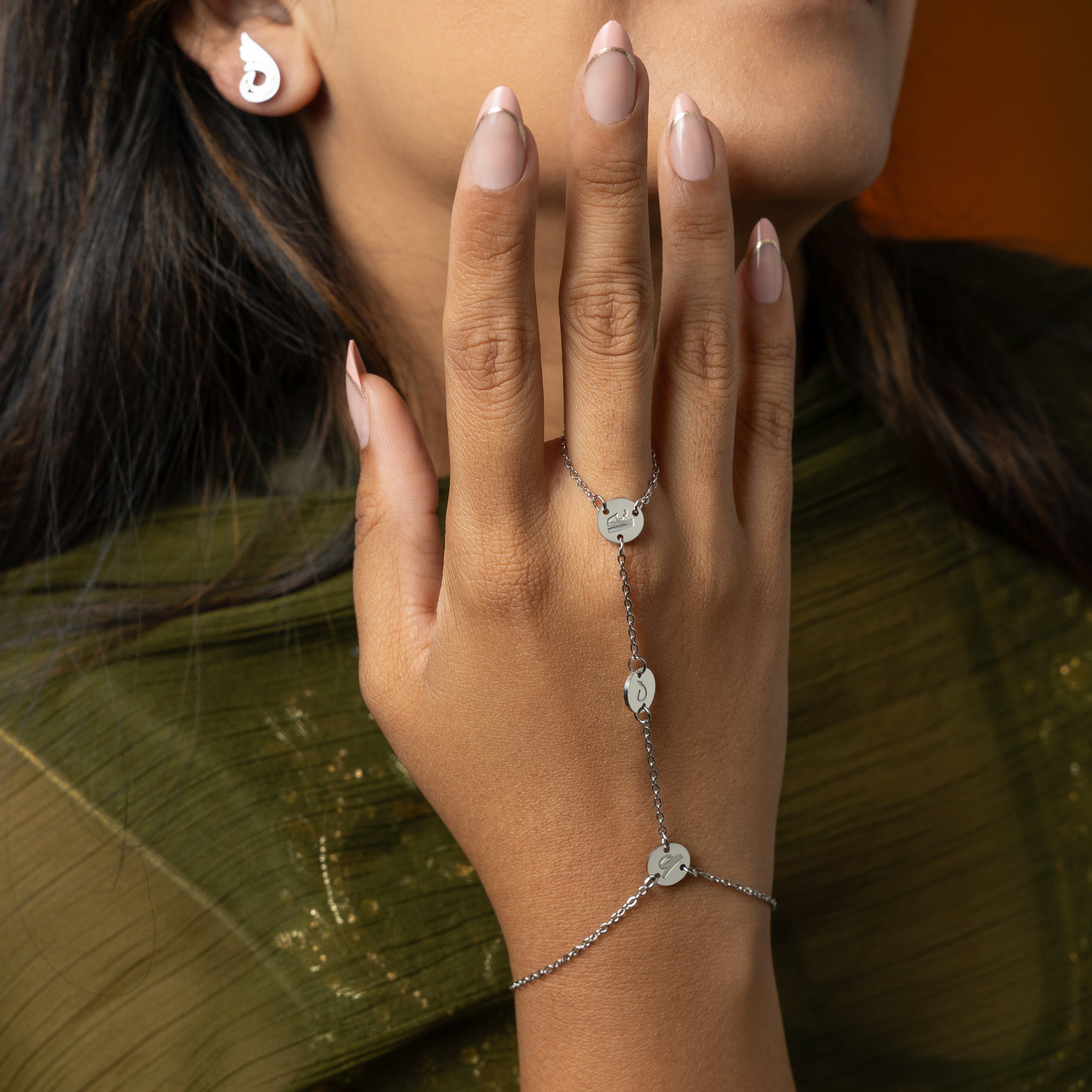 Close-up of the SALAAM hand chain, focusing on the intricate Arabic calligraphy and gold finish