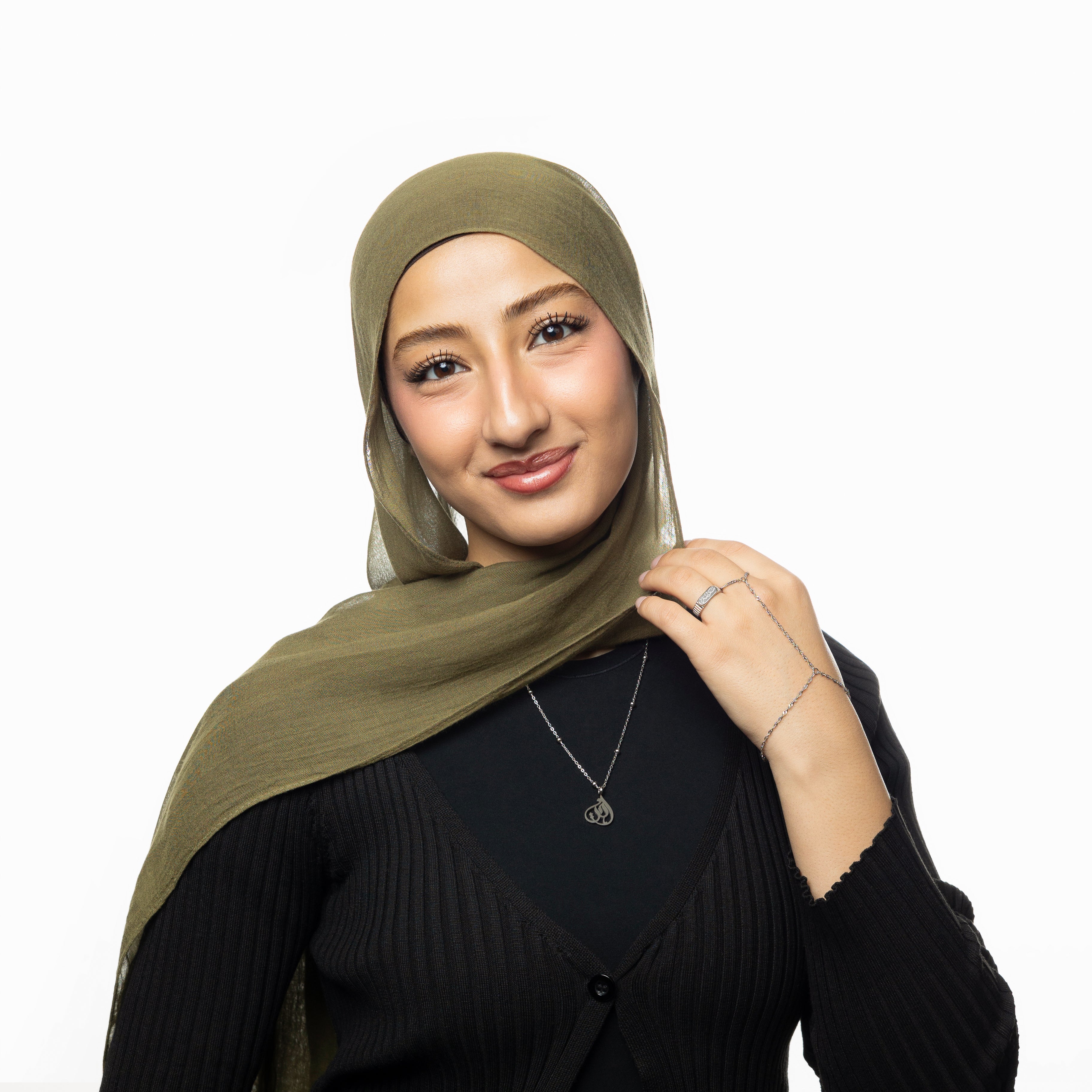 Close-up of Ukhti gold calligraphy pendant on velvet pouch – sister necklace