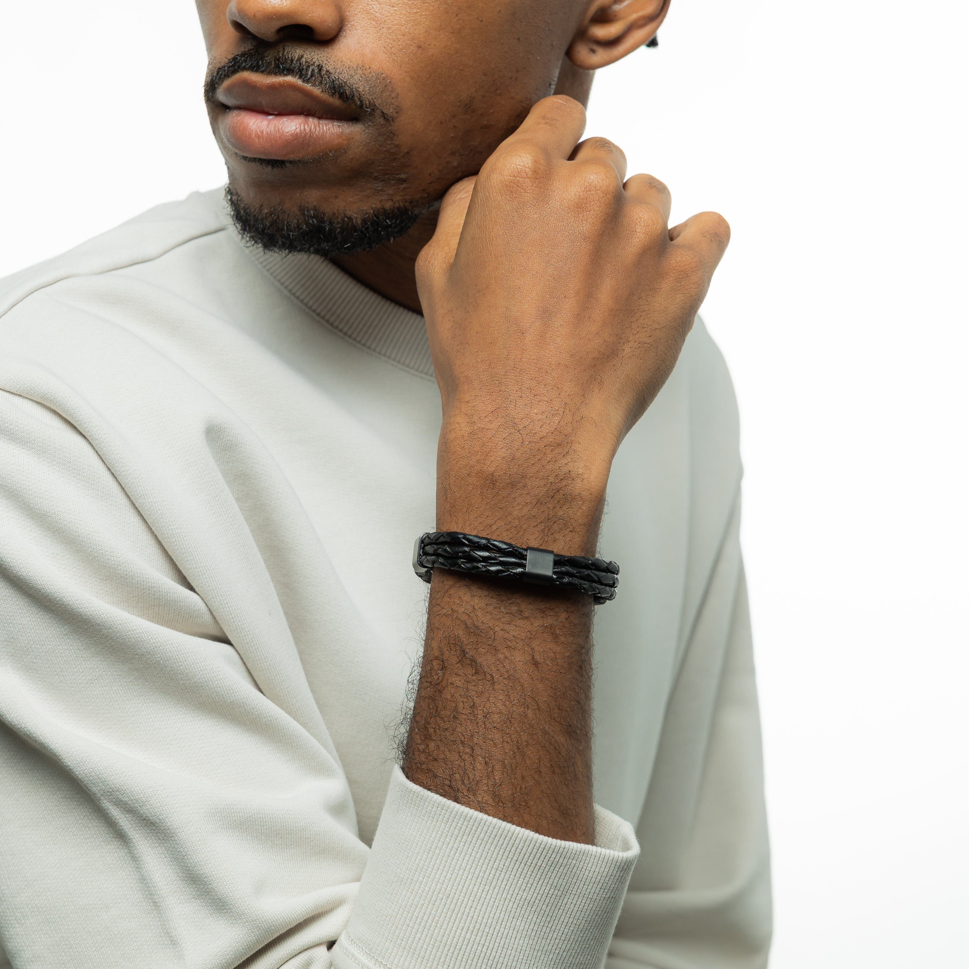 The stylish leather bracelet for men displayed on a wrist in a casual setting.