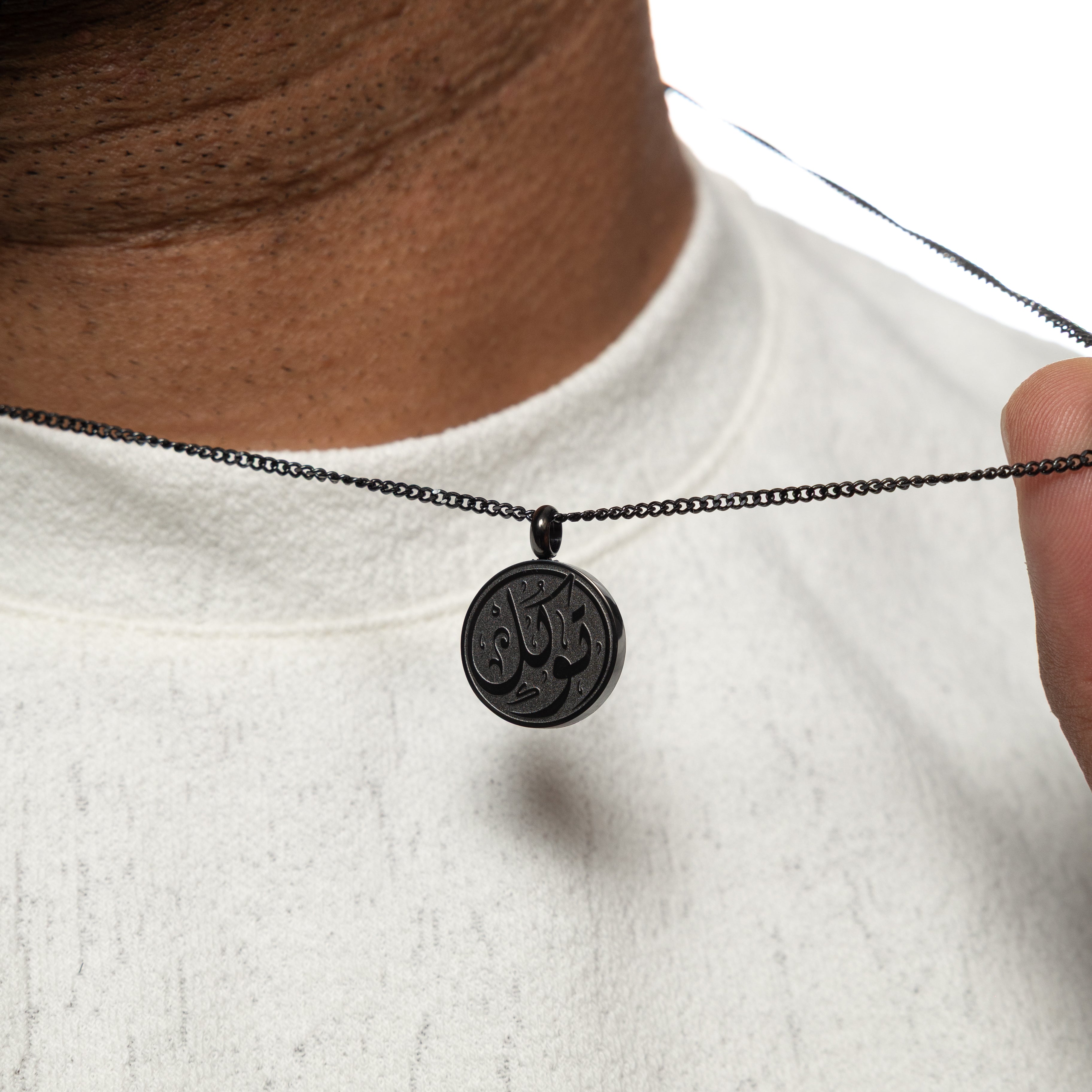 Elegant trust necklace for men showcasing Arabic calligraphy from a side angle.