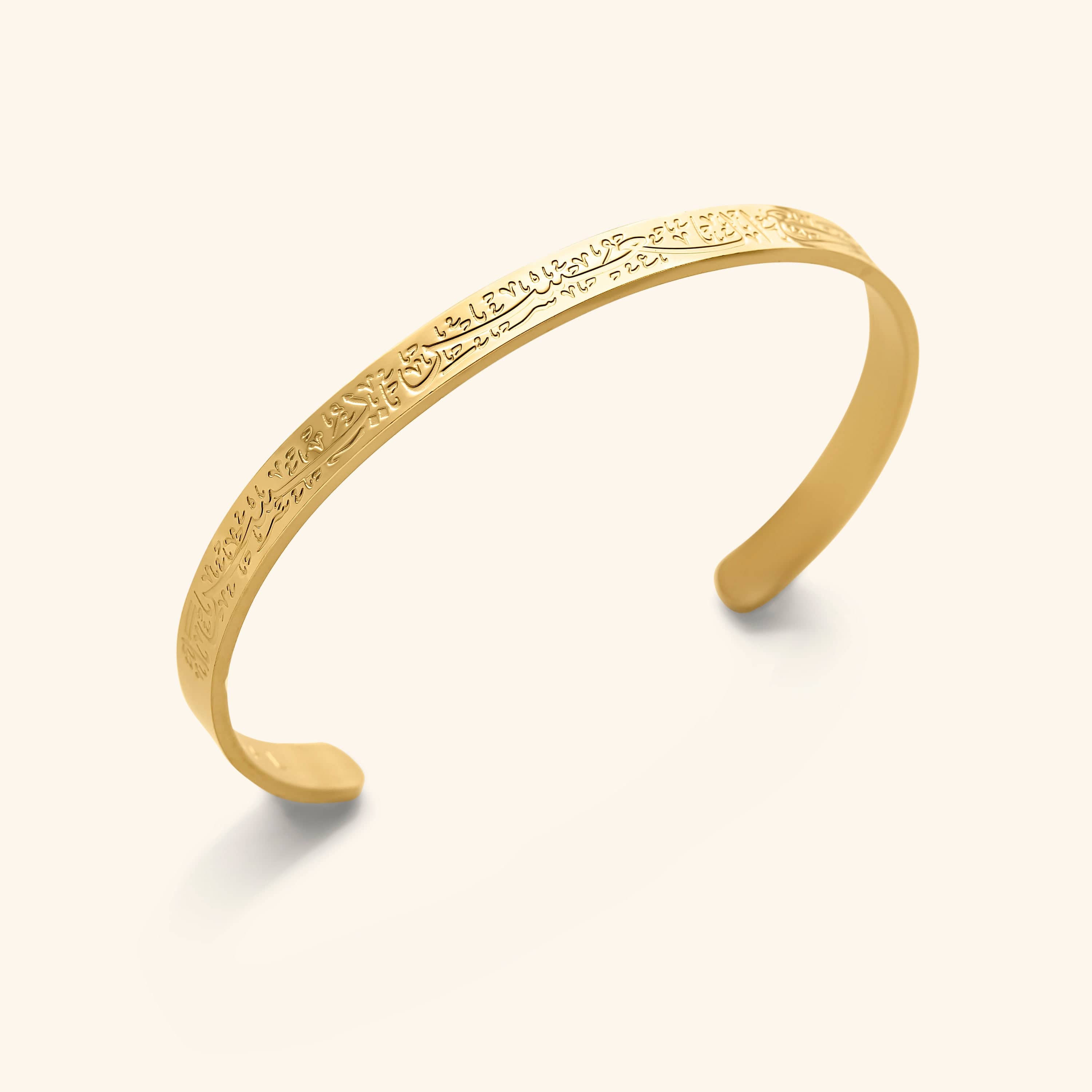 Gold cuff bracelet with Arabic calligraphy, showcasing elegant design and craftsmanship.