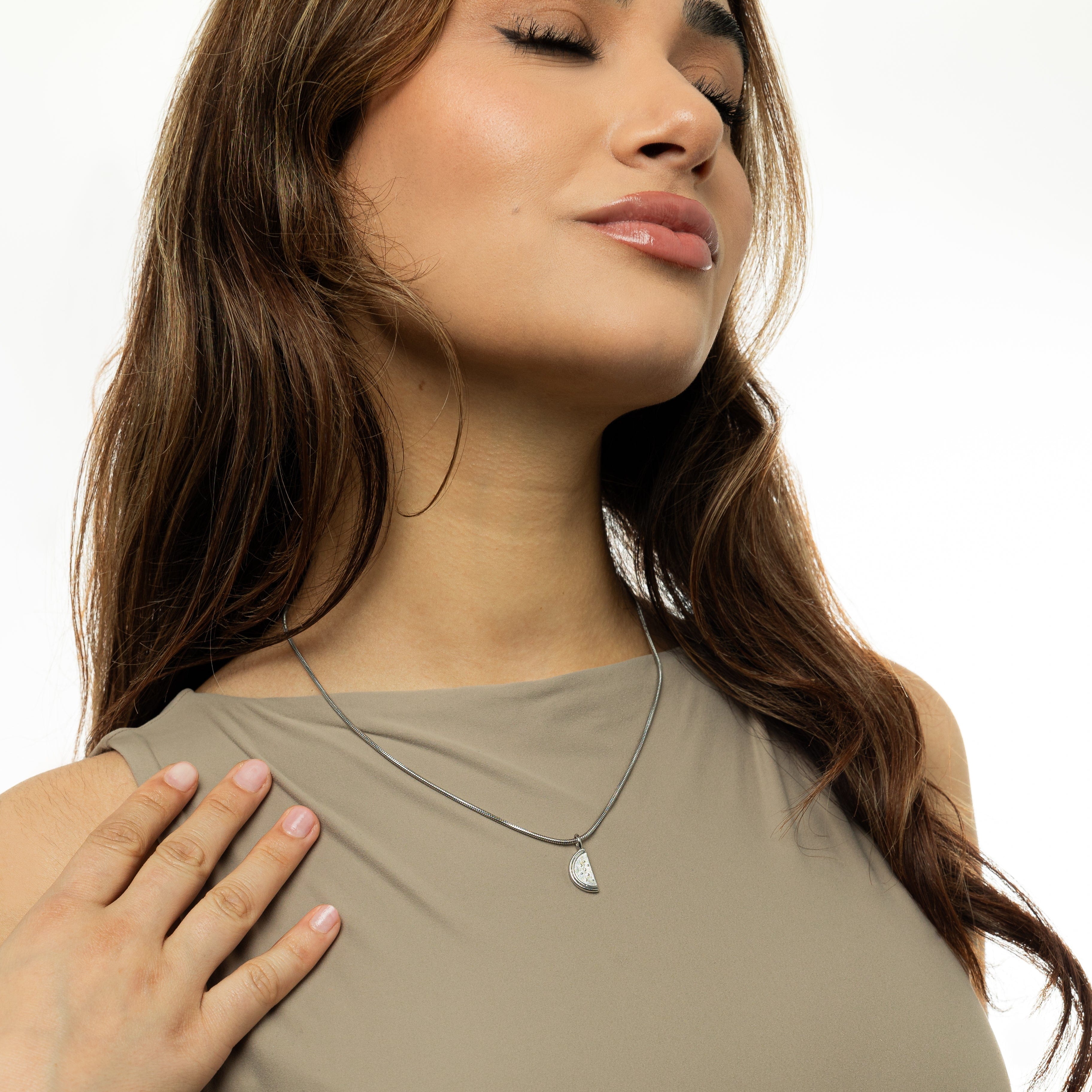 Product display of the watermelon necklace in its velvet pouch, emphasizing its elegant packaging.