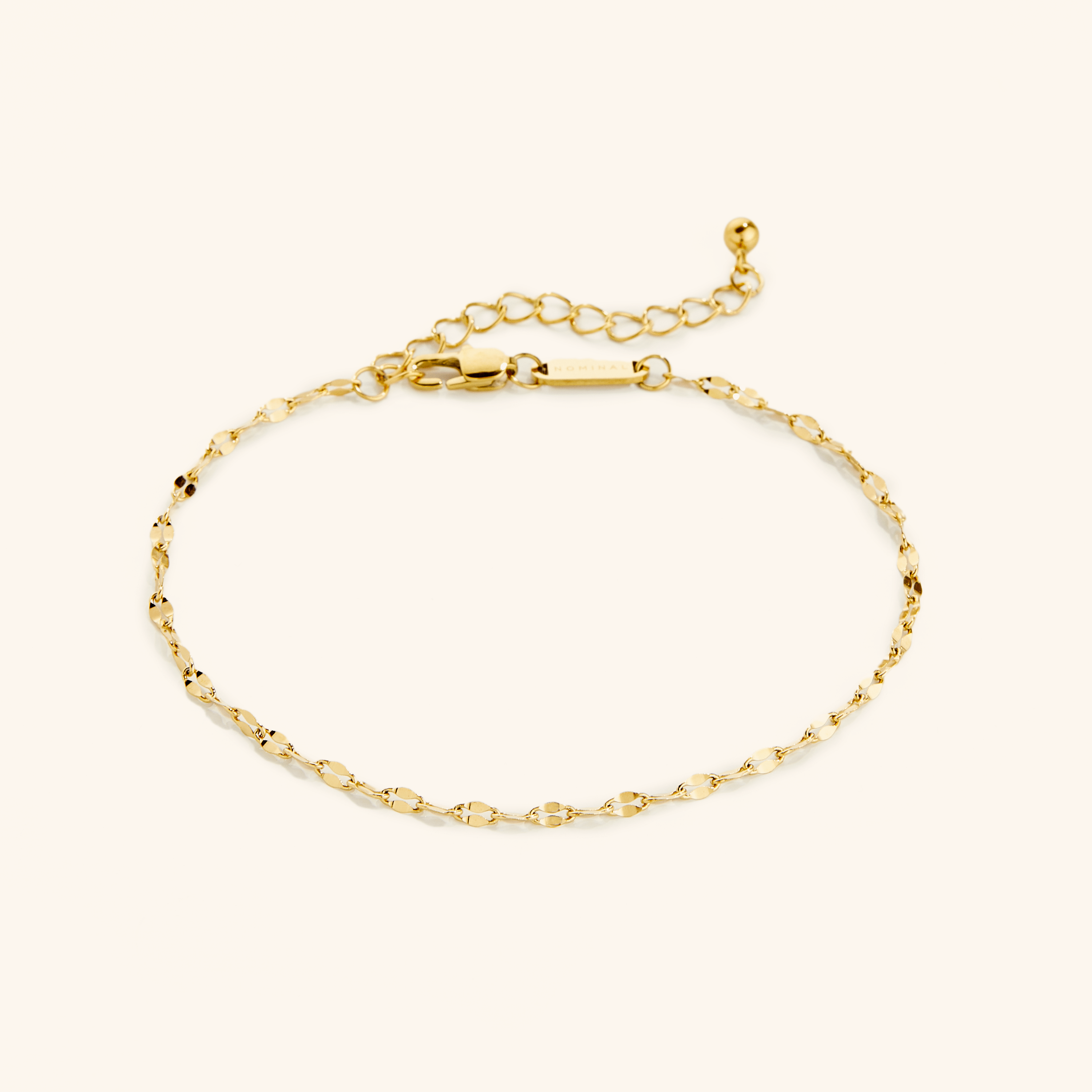 Lustrous Minimalist Gold Anklet displayed elegantly on a soft surface, showcasing its shiny finish.