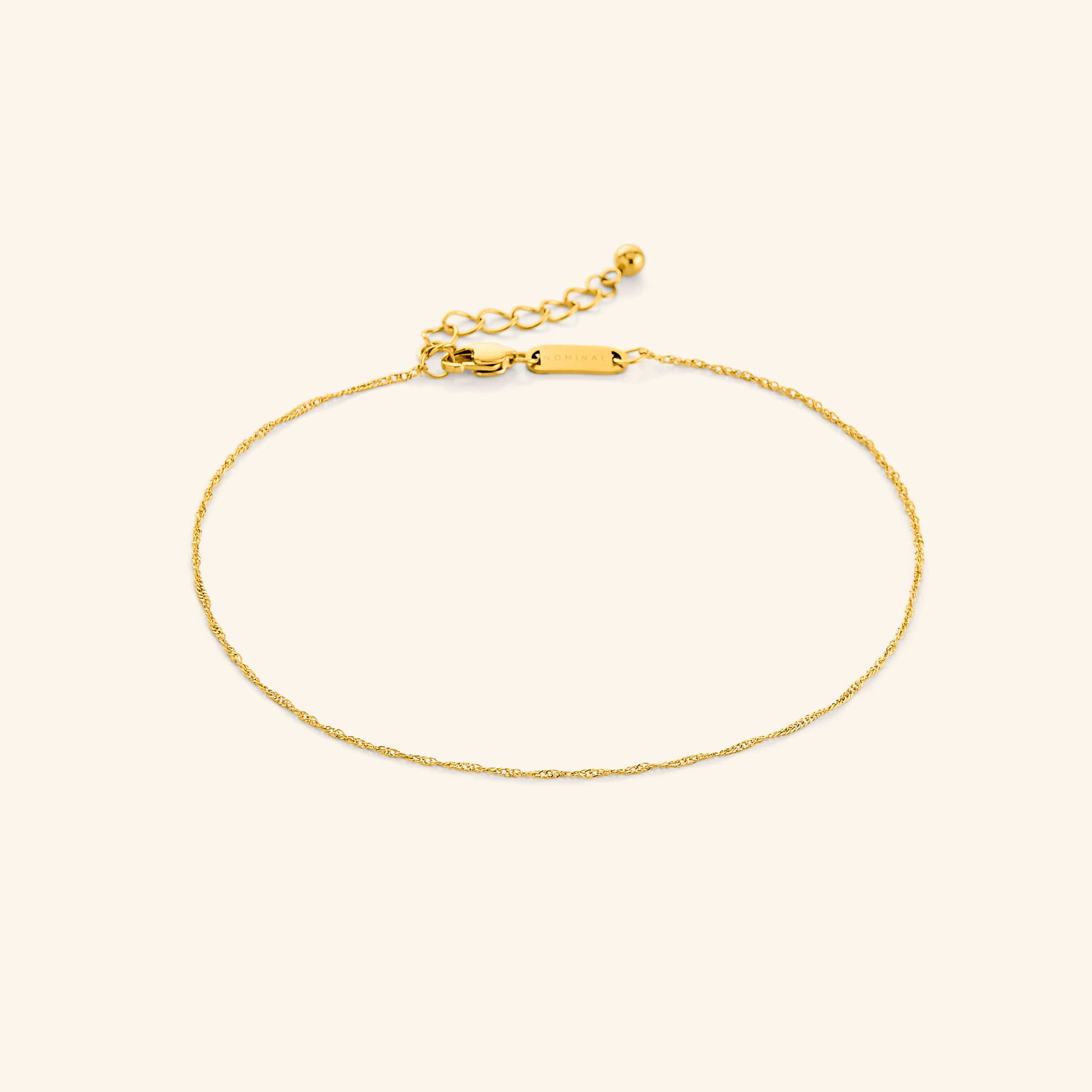 Close-up of the micro twisted gold anklet laid flat on velvet pouch