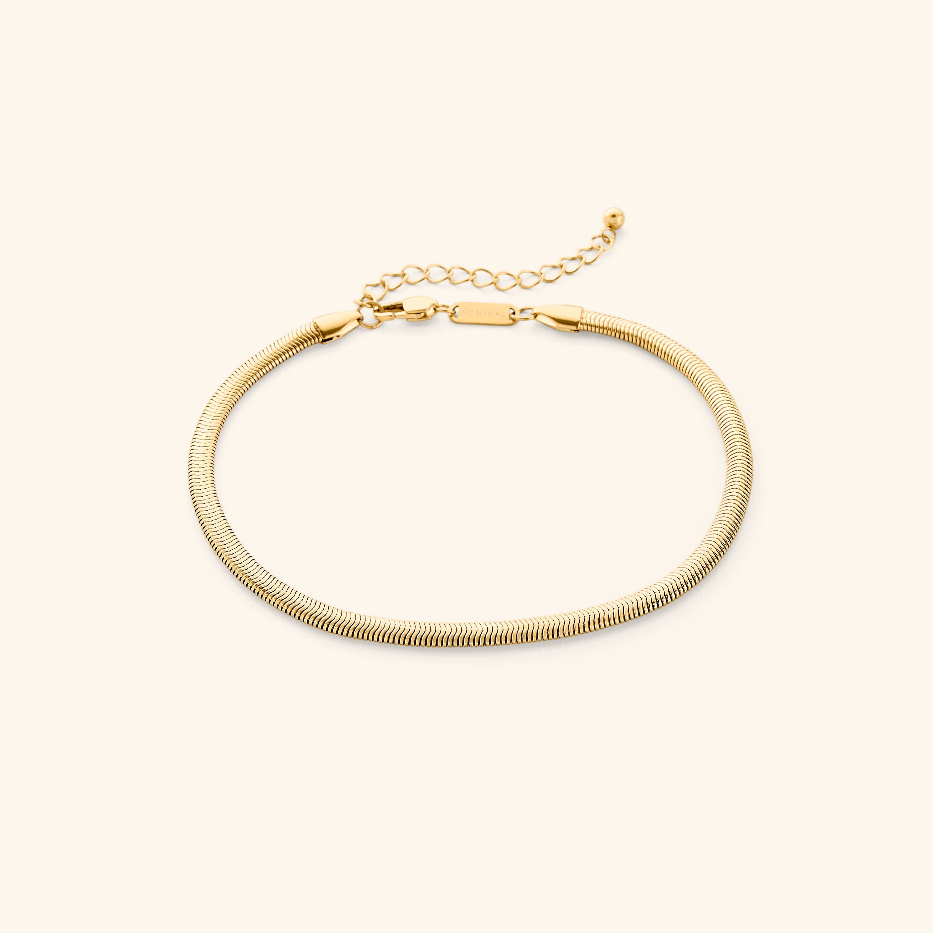 Chic liquid gold snake anklet displaying its sleek design and shine against a neutral background.