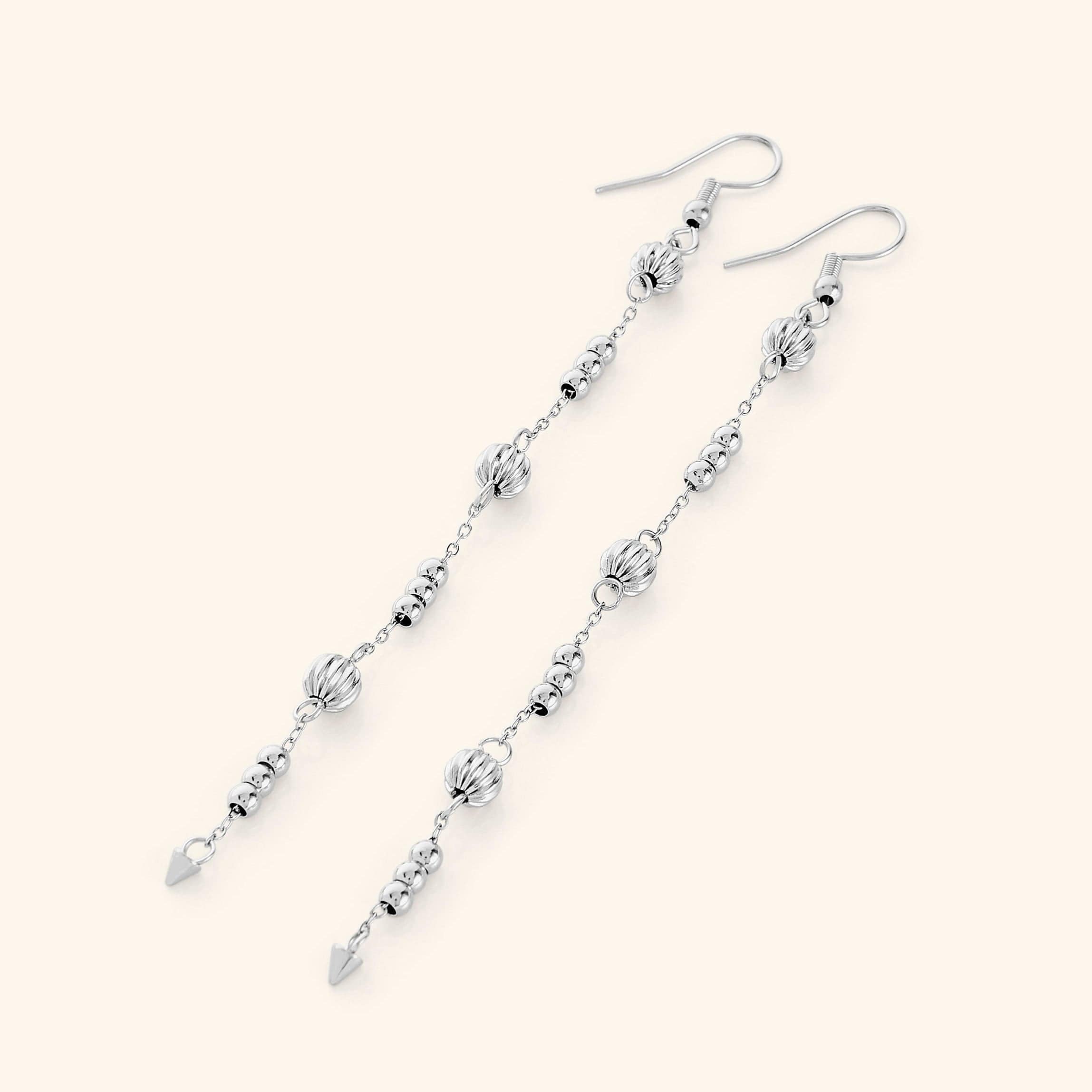 Close-up of gold dangle earrings highlighting their delicate orbs and craftsmanship.