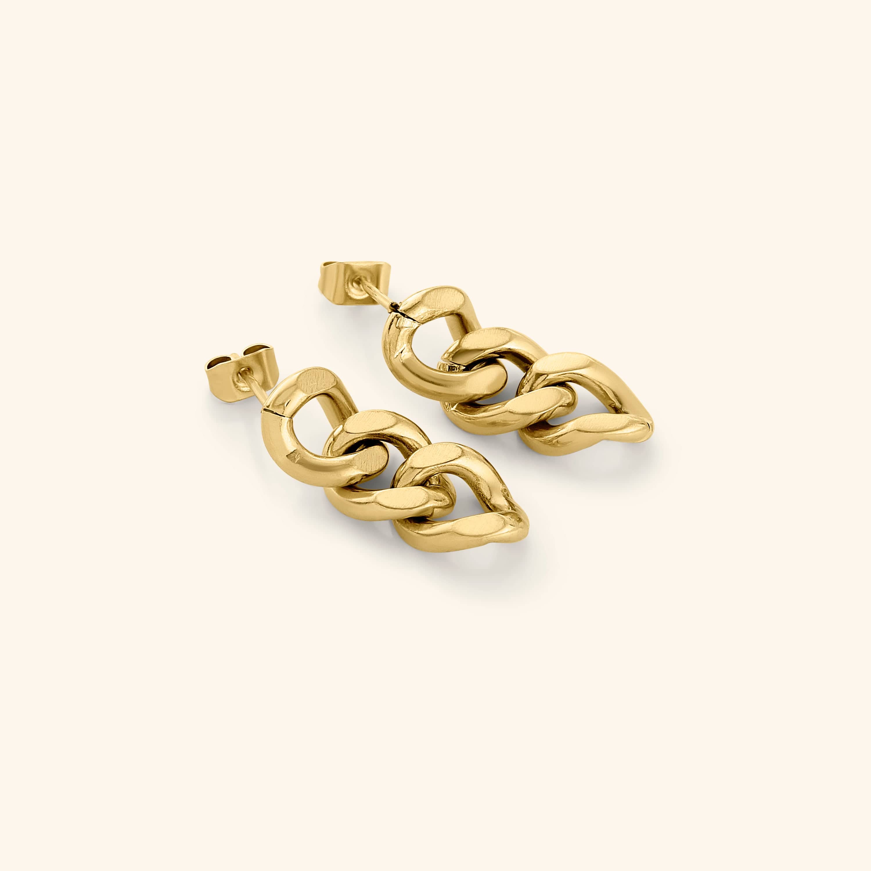 Close-up of bold Cuban gold dangle earrings showcasing the three-link design.