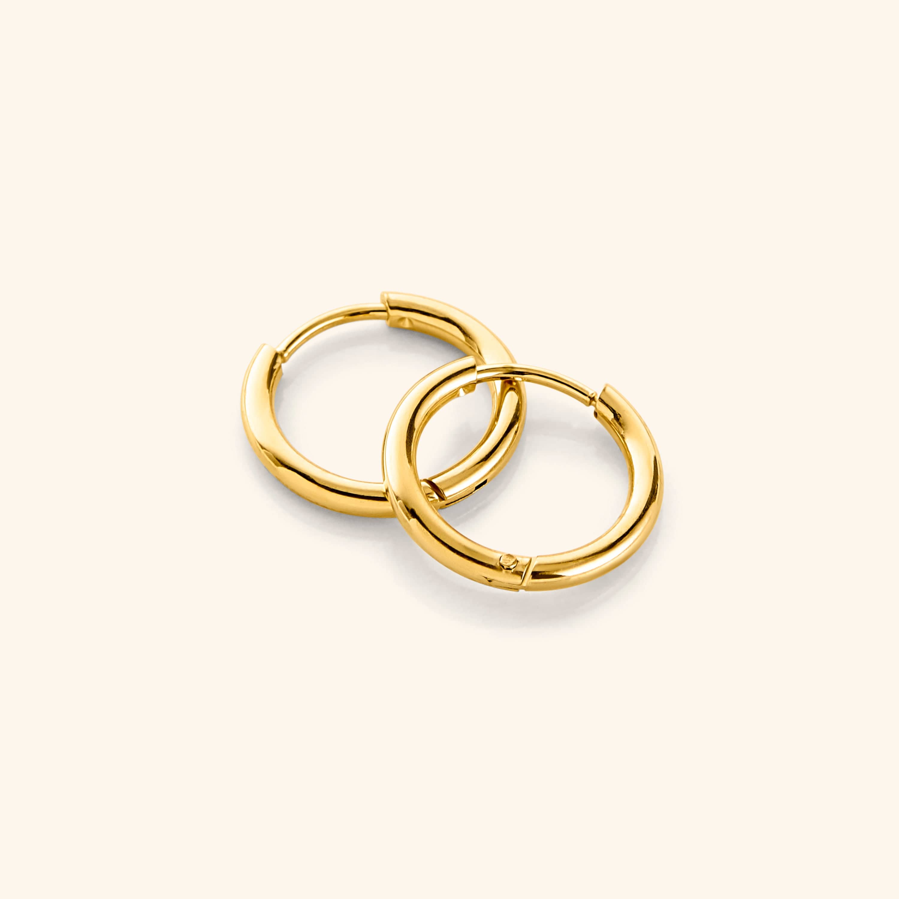 Chic 18K gold huggie earrings displayed on a model's ear, showcasing their elegant design.