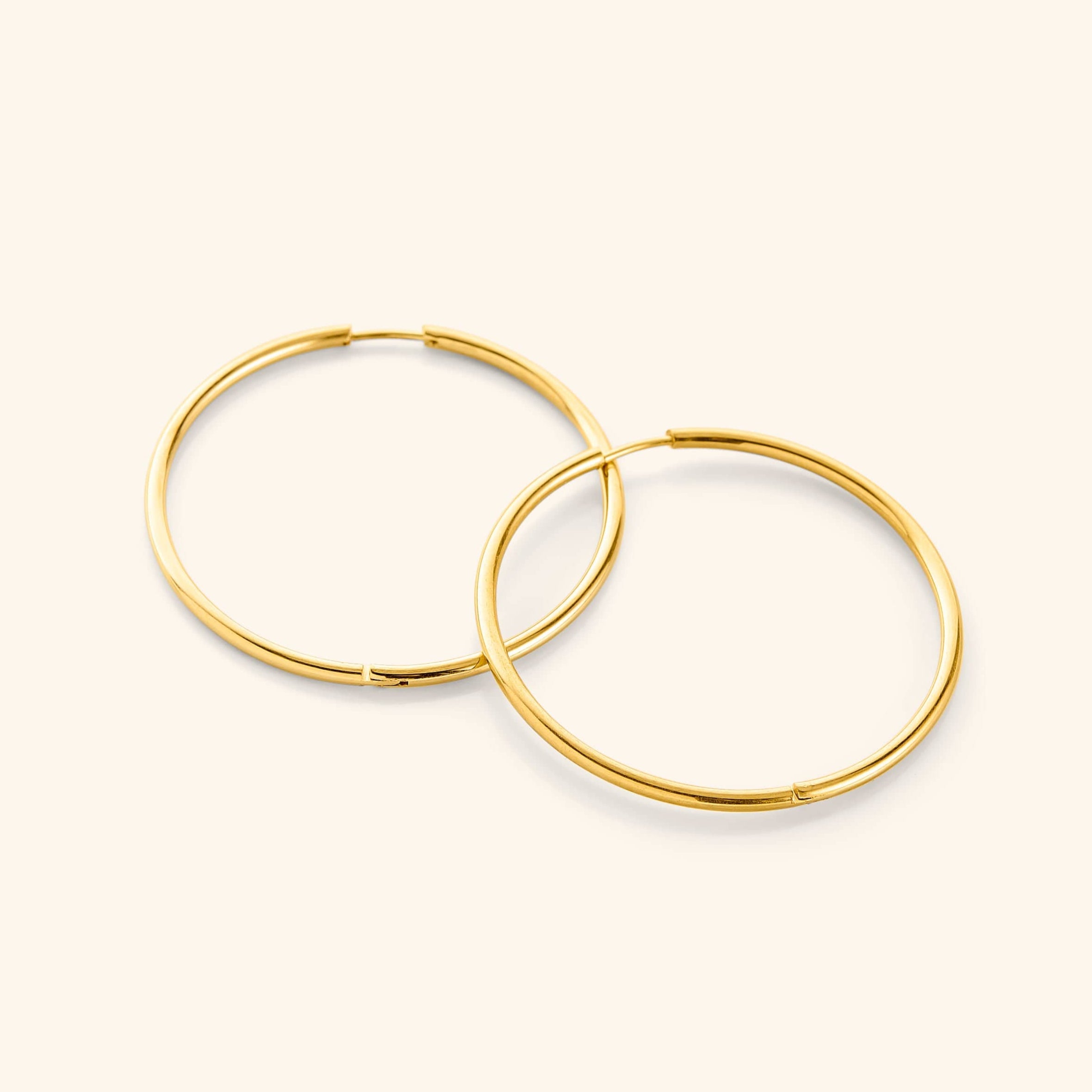 Close-up of bold 40mm gold hoop earrings showcasing the shine and details.