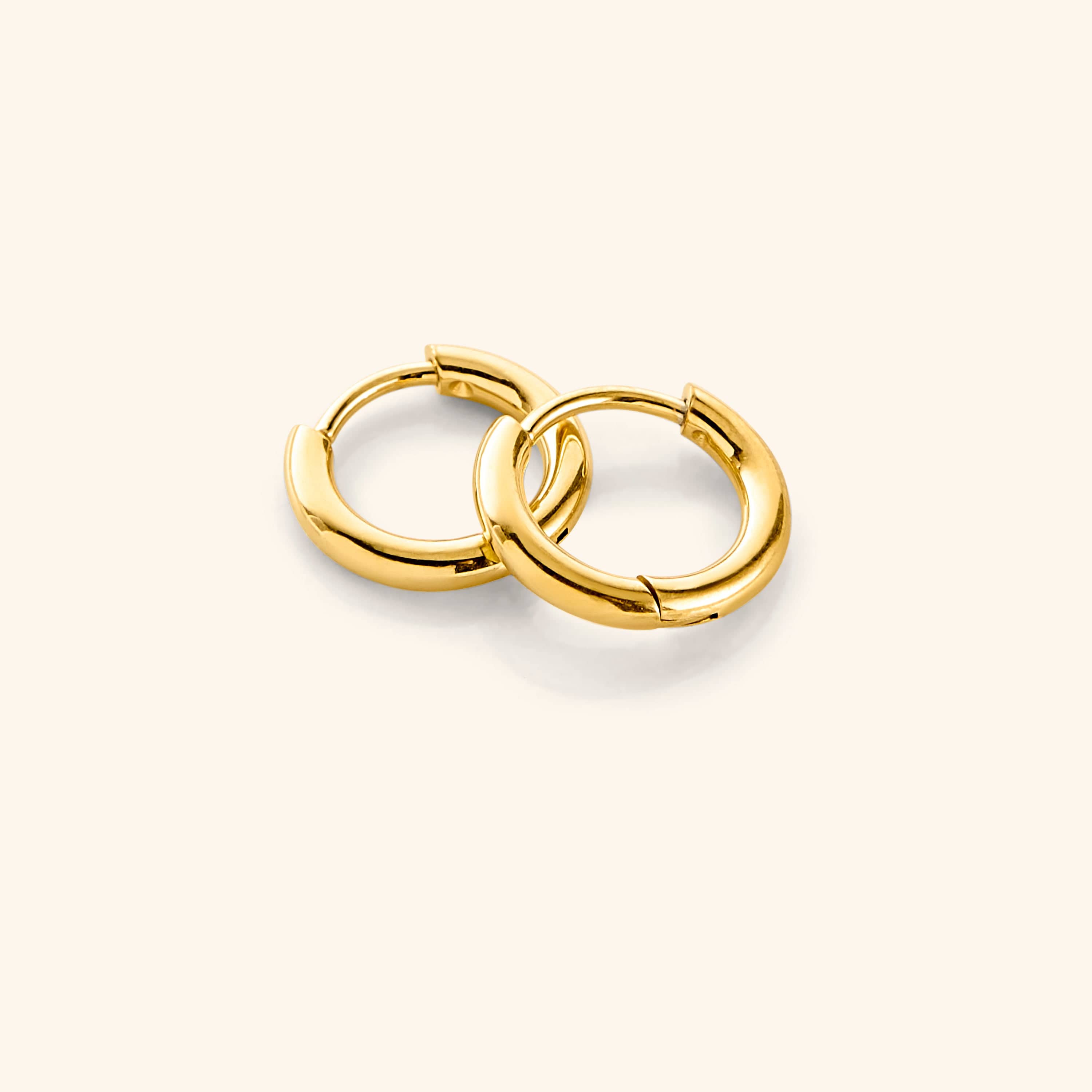 Essential 8mm gold huggie earrings in a close-up view showcasing the delicate design and 18 Karat gold plating.